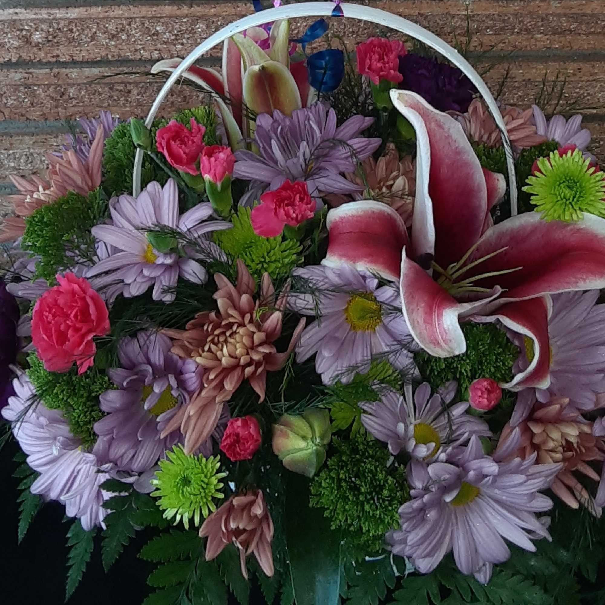 Mixed bouquet with pink lilies and lavender daisies in a basket handle arrangement