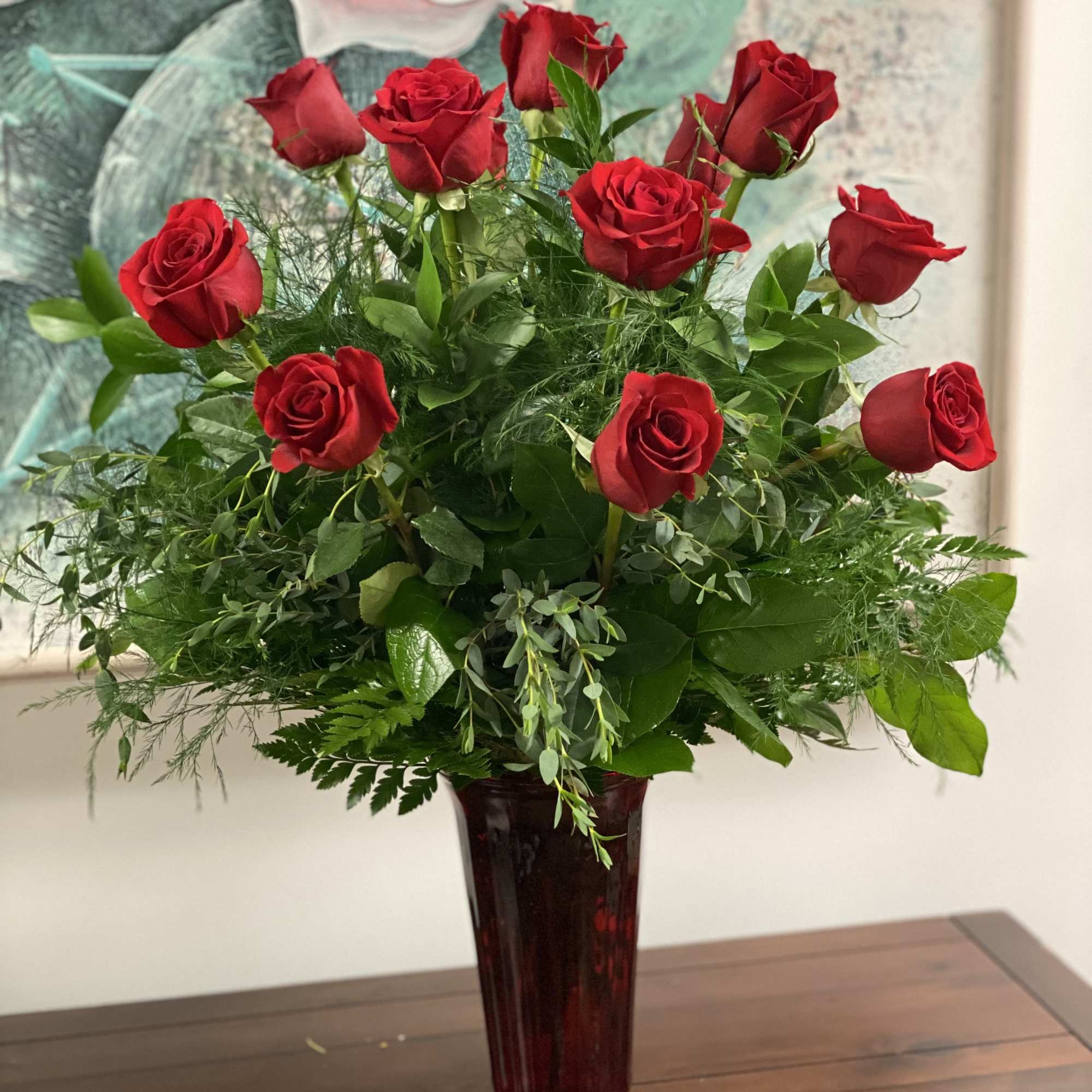 Red roses arranged in a tall burgundy vase