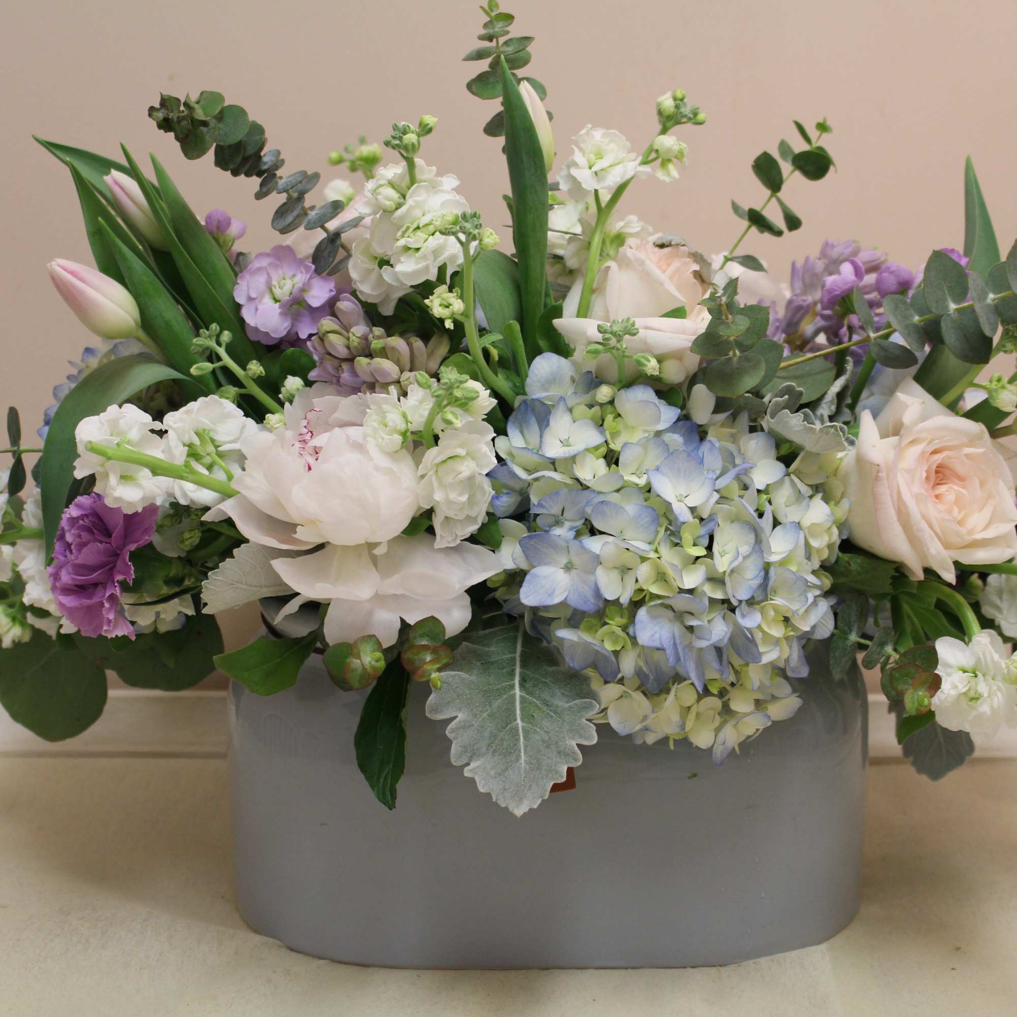 Mixed pastel floral arrangement in a gray container
