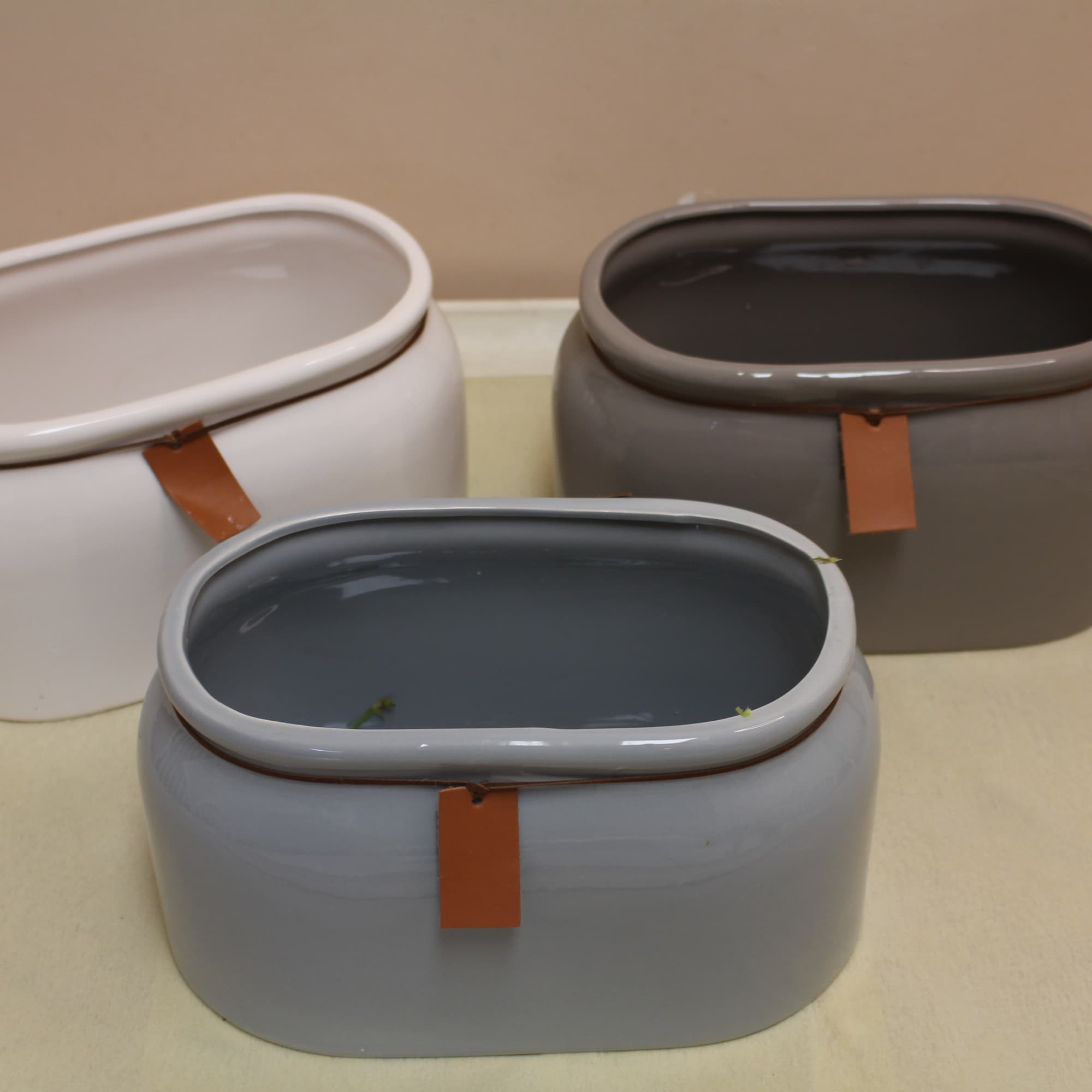 Three oval ceramic planters in white, gray, and taupe on a tray