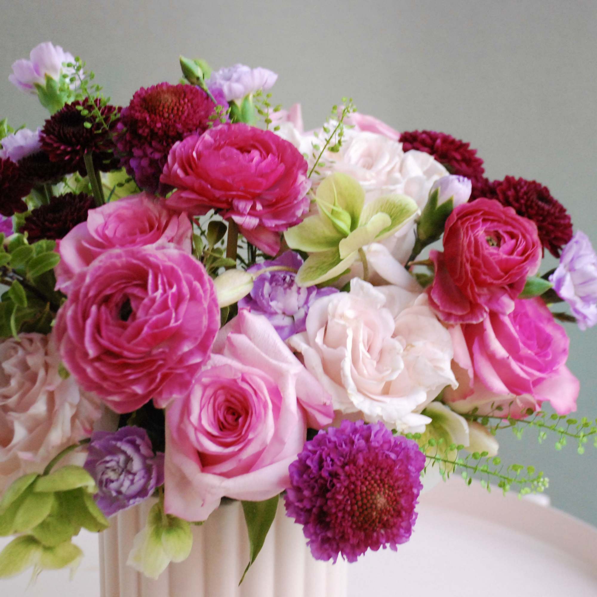 Pink and white floral arrangement in a pale vase