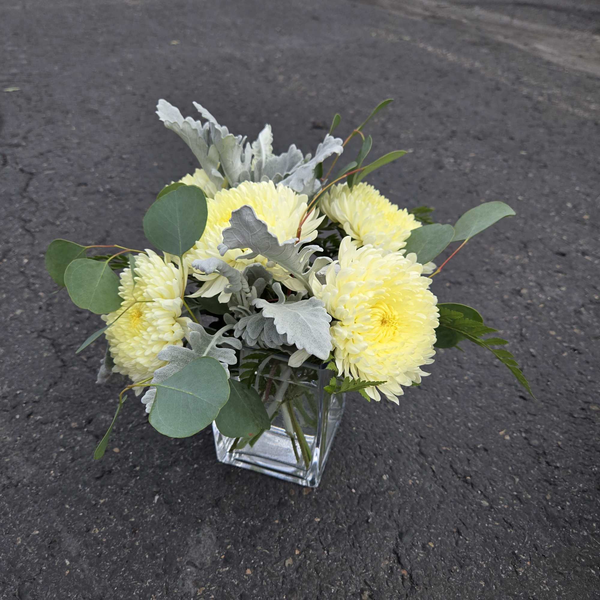 Yellow chrysanthemum bouquet in a clear square vase