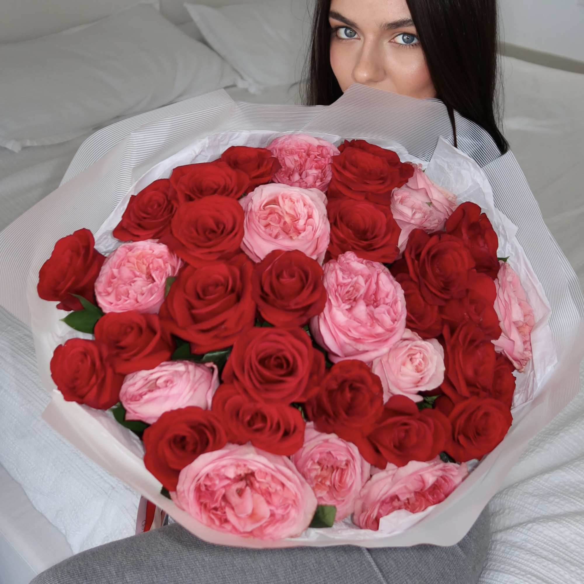 Woman holding a large bouquet of red and pink roses