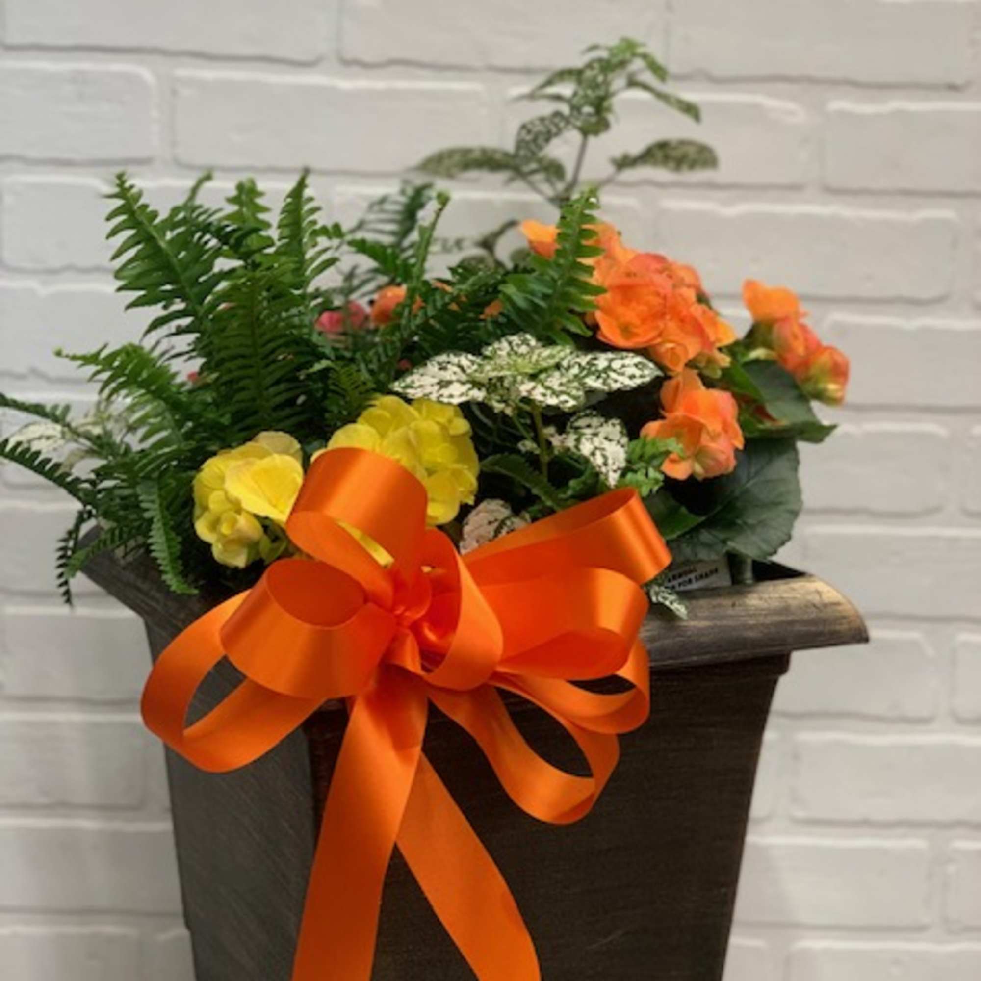 Orange and yellow flower arrangement in a dark box with a large orange ribbon