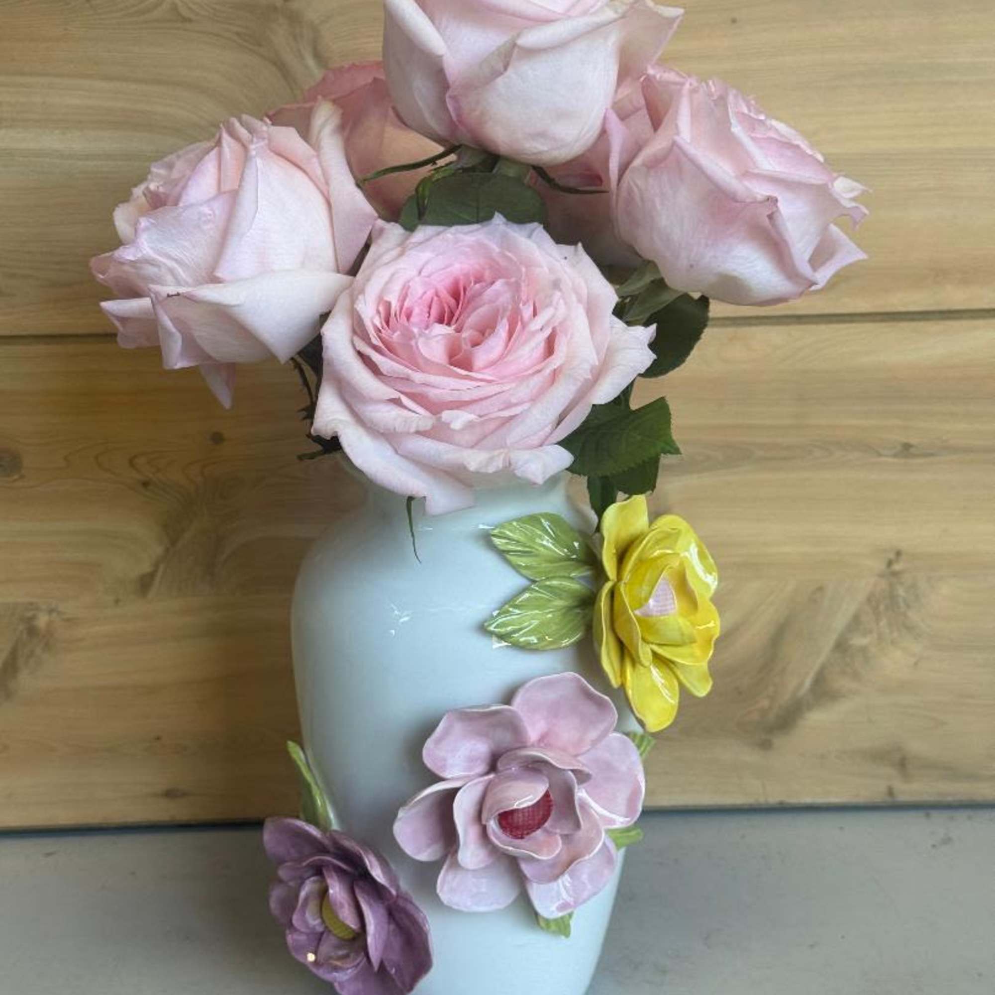 Soft assorted tulips arching from a glossy white ceramic vase give this