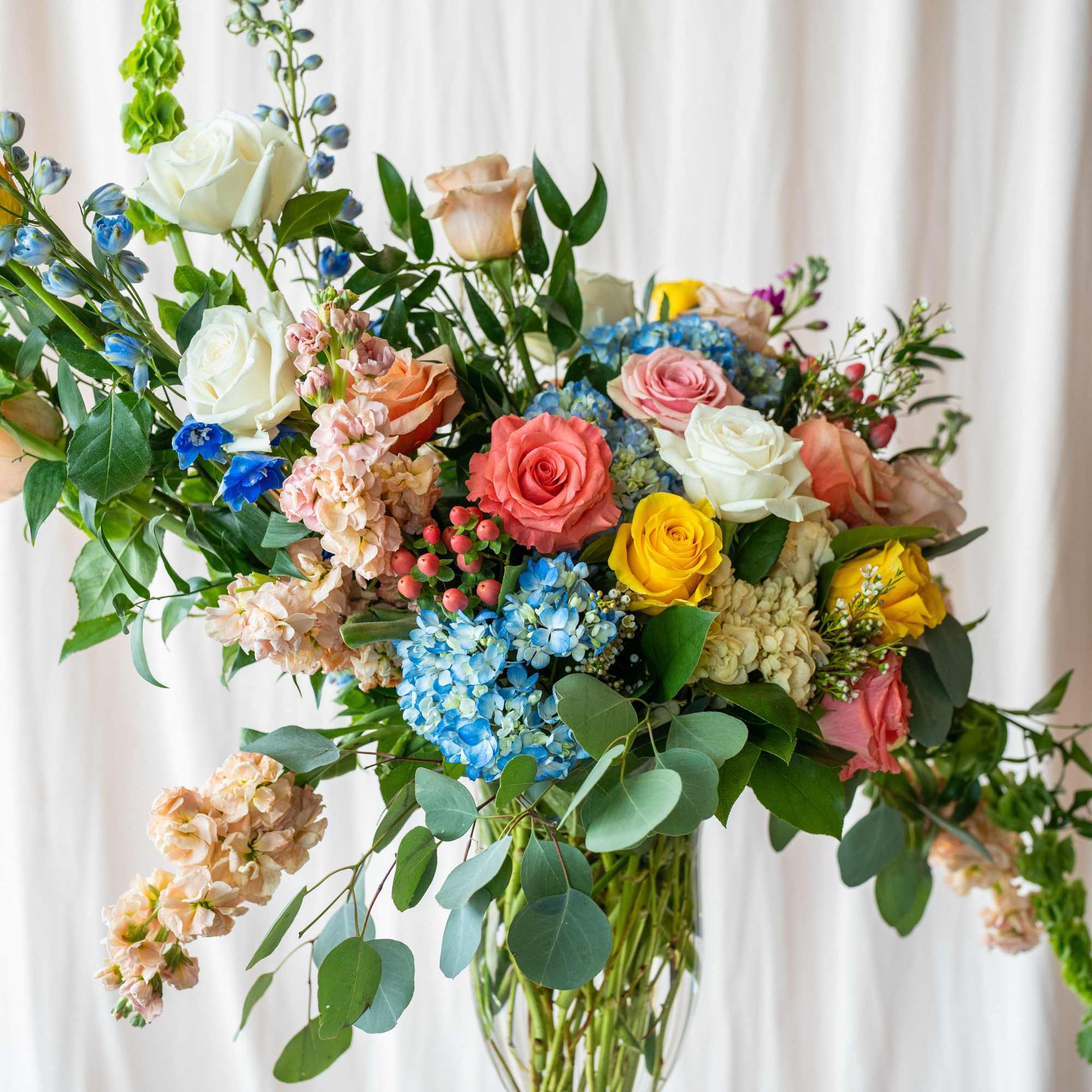 Mixed bouquet of roses and blue hydrangeas in a clear glass vase