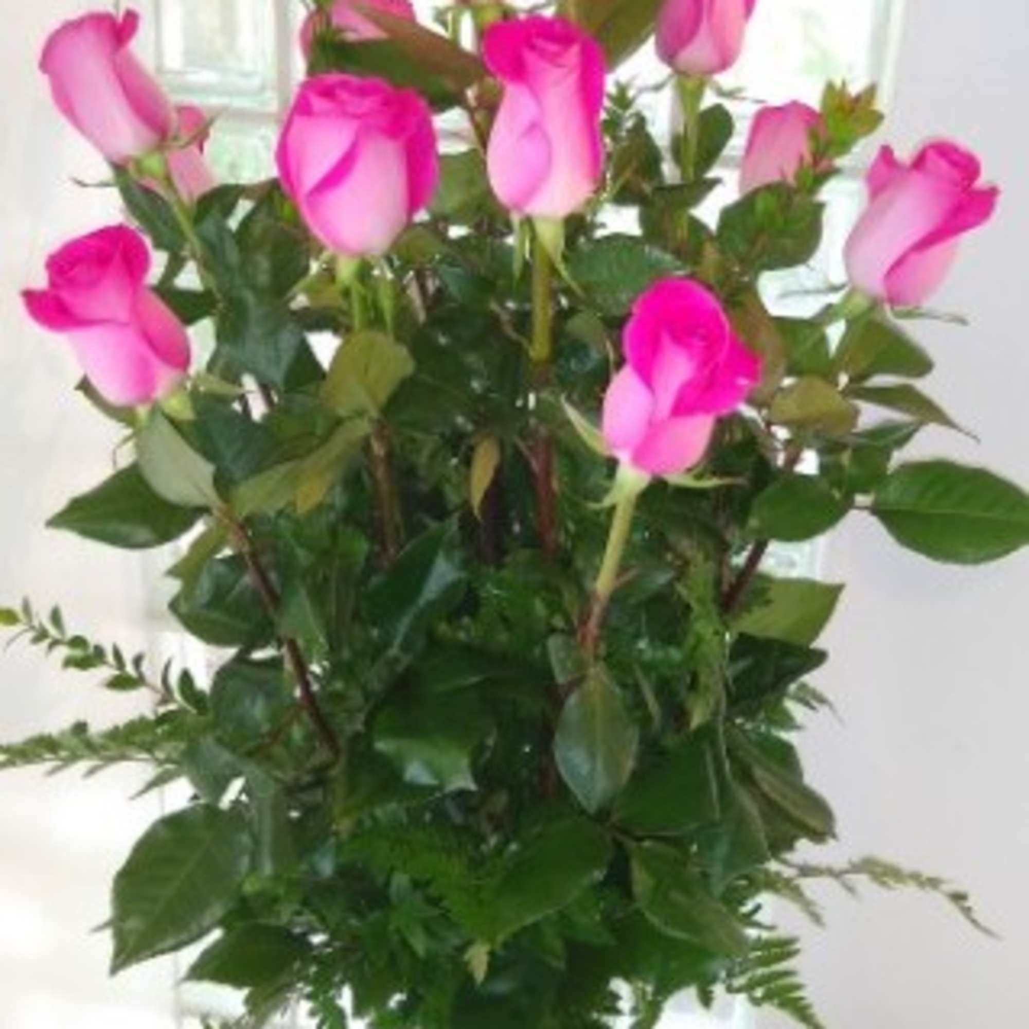 Pink roses arranged in a clear glass vase with greenery