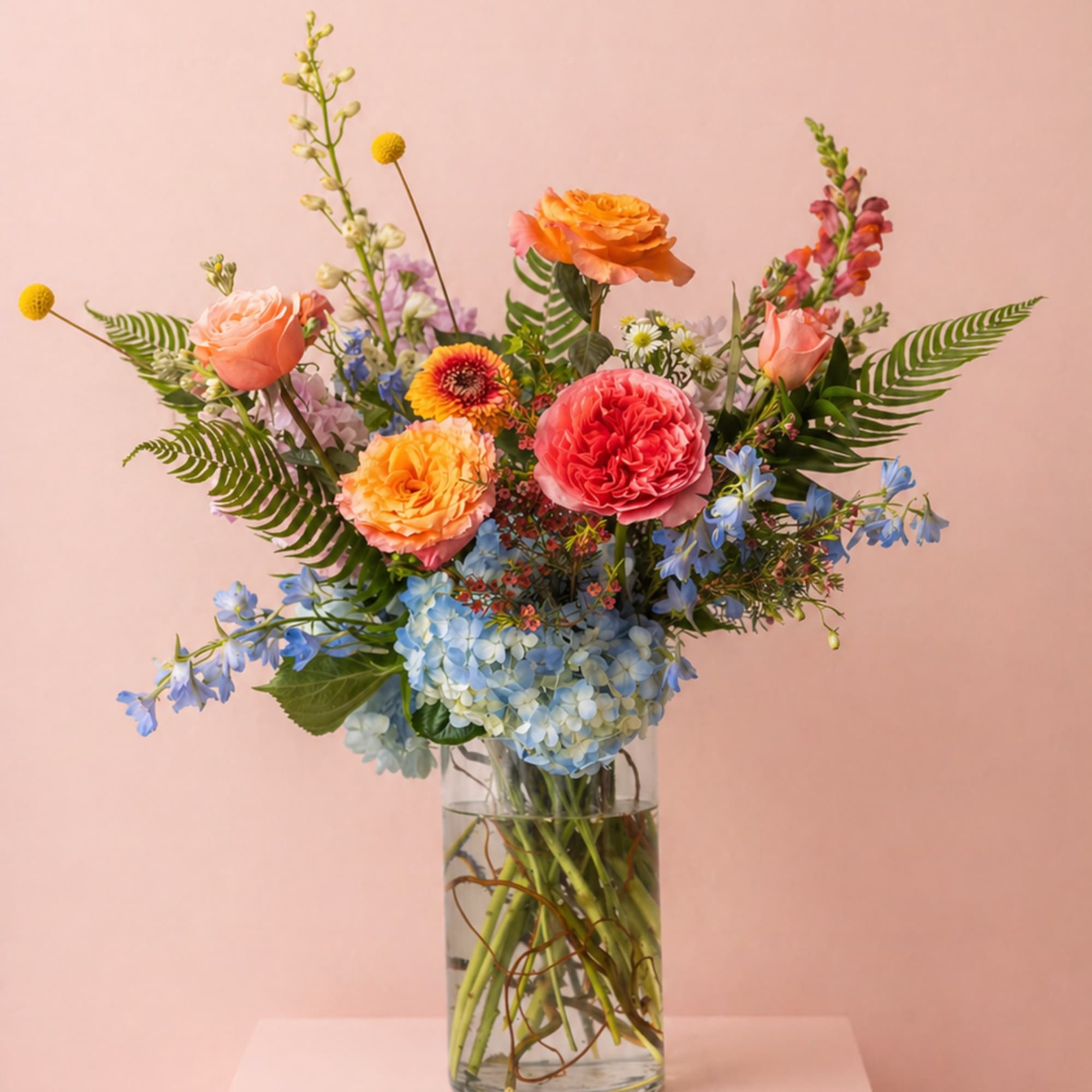 A vibrant, garden-style arrangement filled with layered seasonal blooms in soft pastels