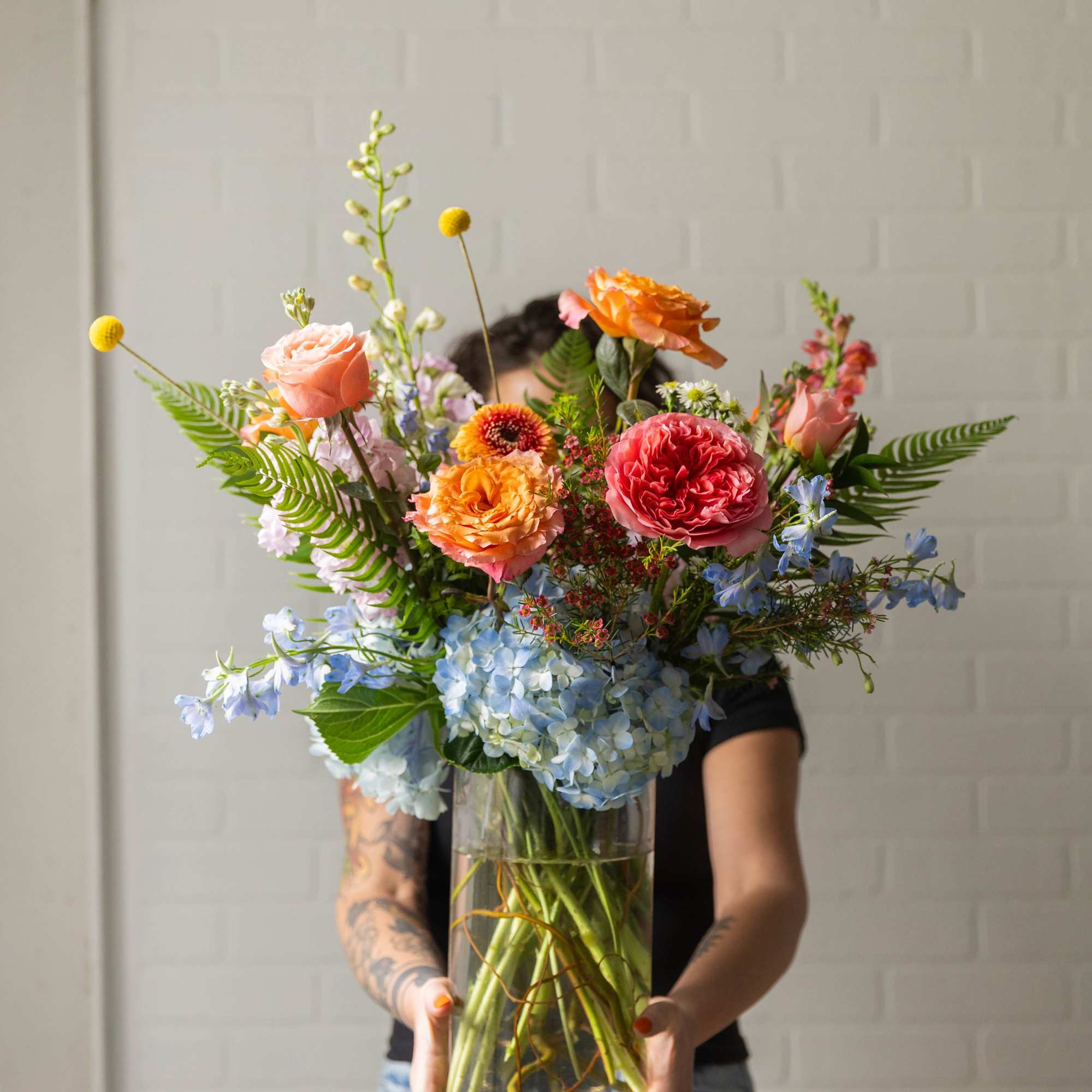 A vibrant, garden-style arrangement filled with layered seasonal blooms in soft pastels