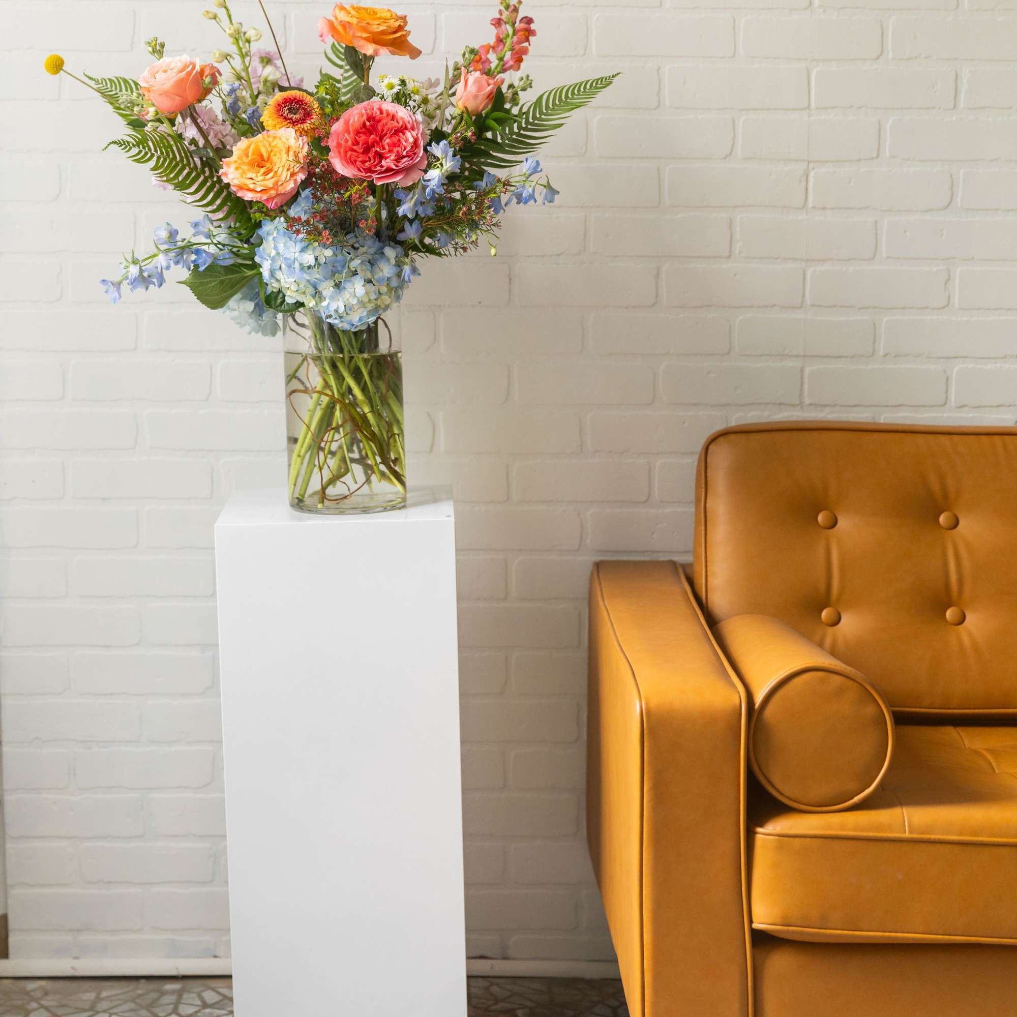 A vibrant, garden-style arrangement filled with layered seasonal blooms in soft pastels