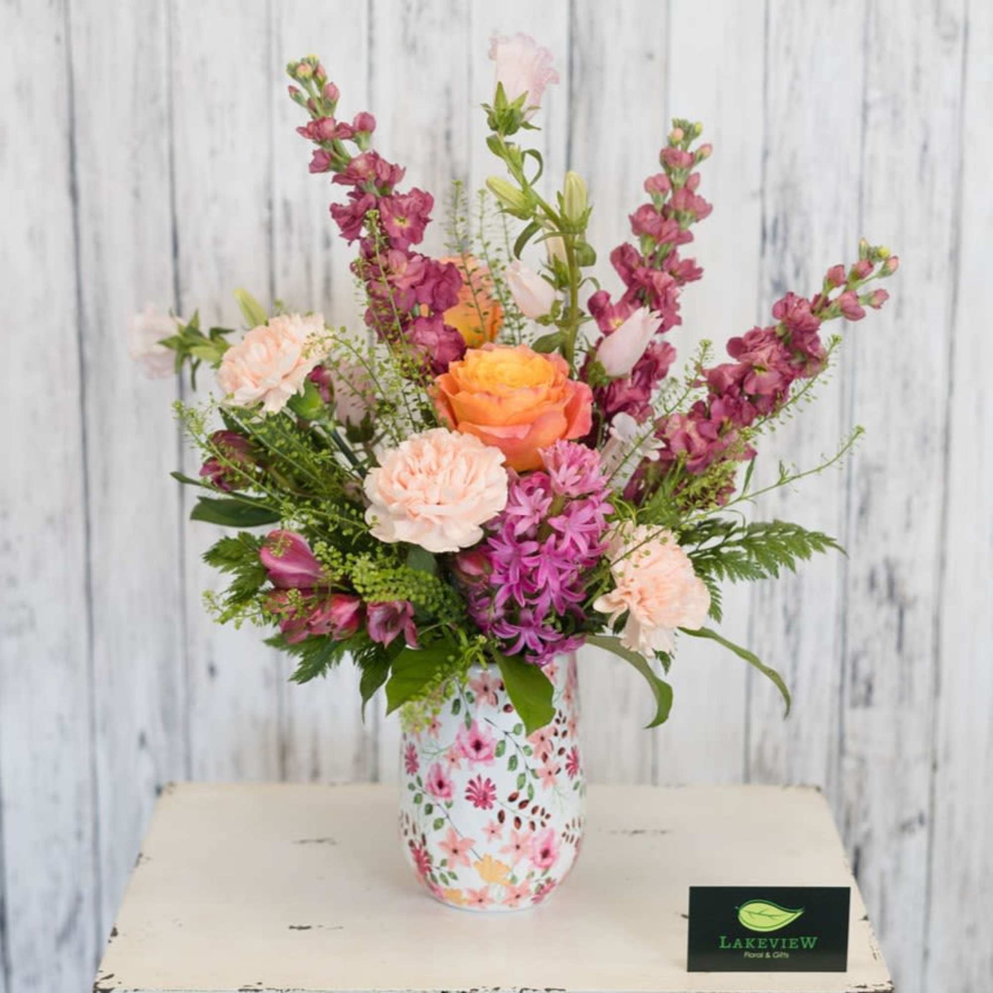 Sunset toned roses and peach carnations mingle with tall mauve stock blossoms