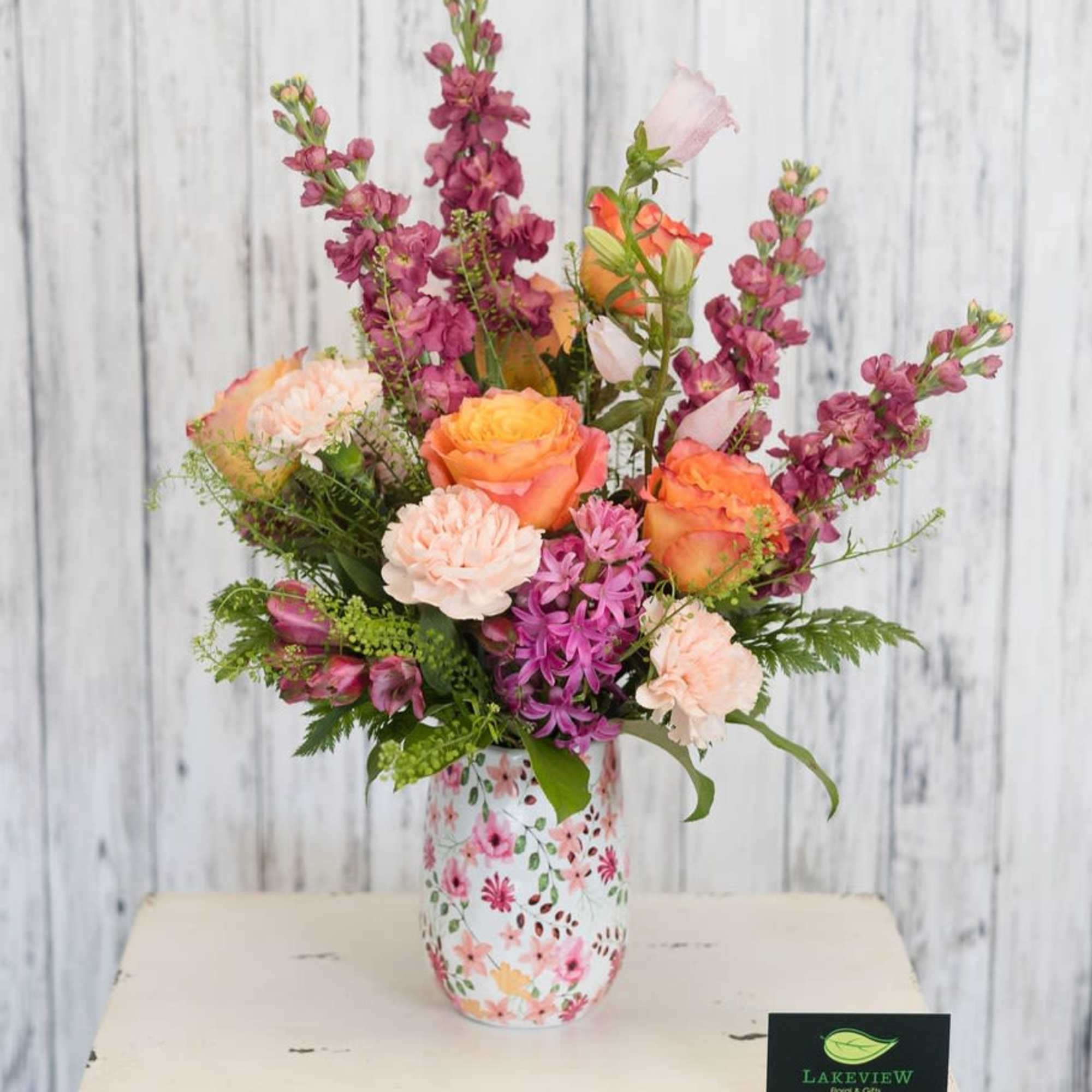Sunset toned roses and peach carnations mingle with tall mauve stock blossoms