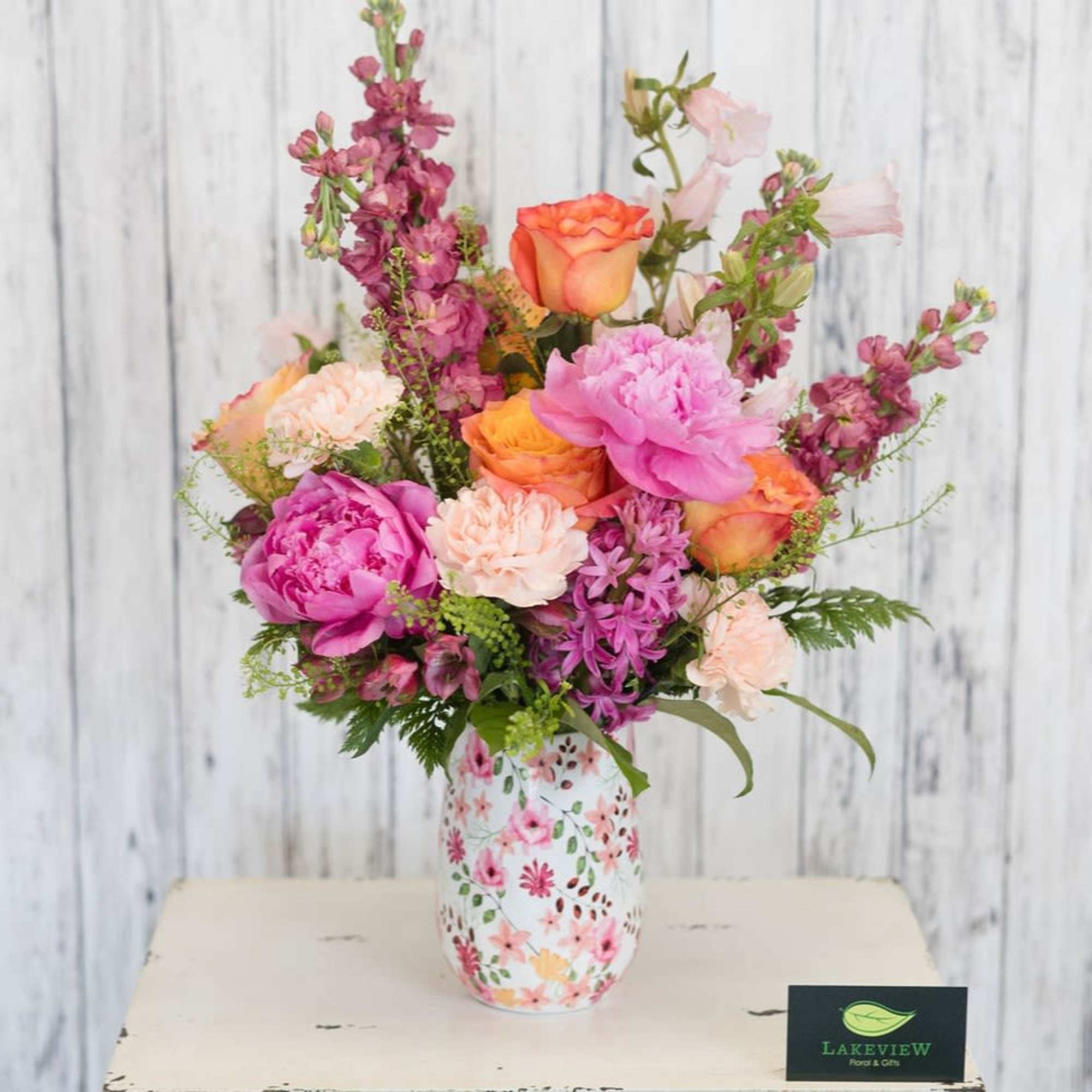 Sunset toned roses and peach carnations mingle with tall mauve stock blossoms