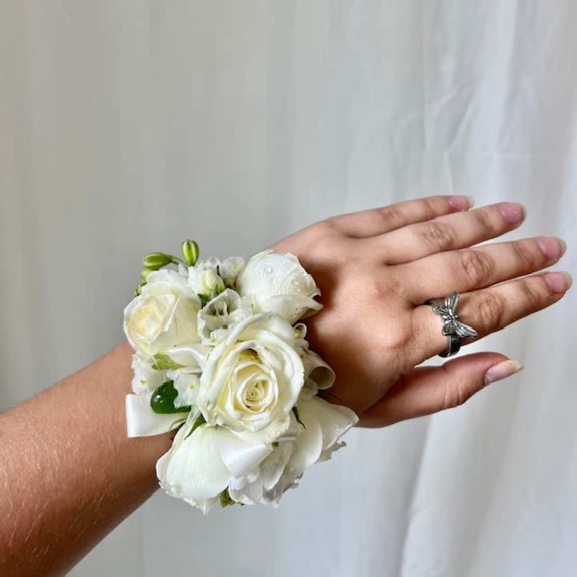 White rose wrist corsage with ribbon on a hand
