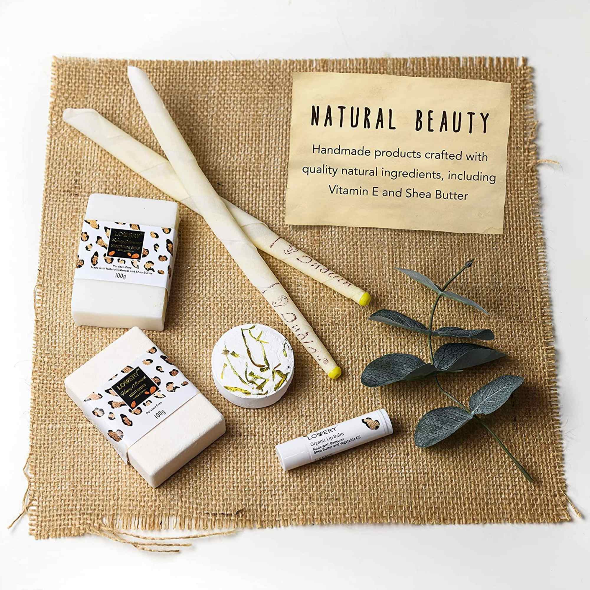 Natural beauty gift set with soaps, candles, lip balm, and greenery on a burlap mat
