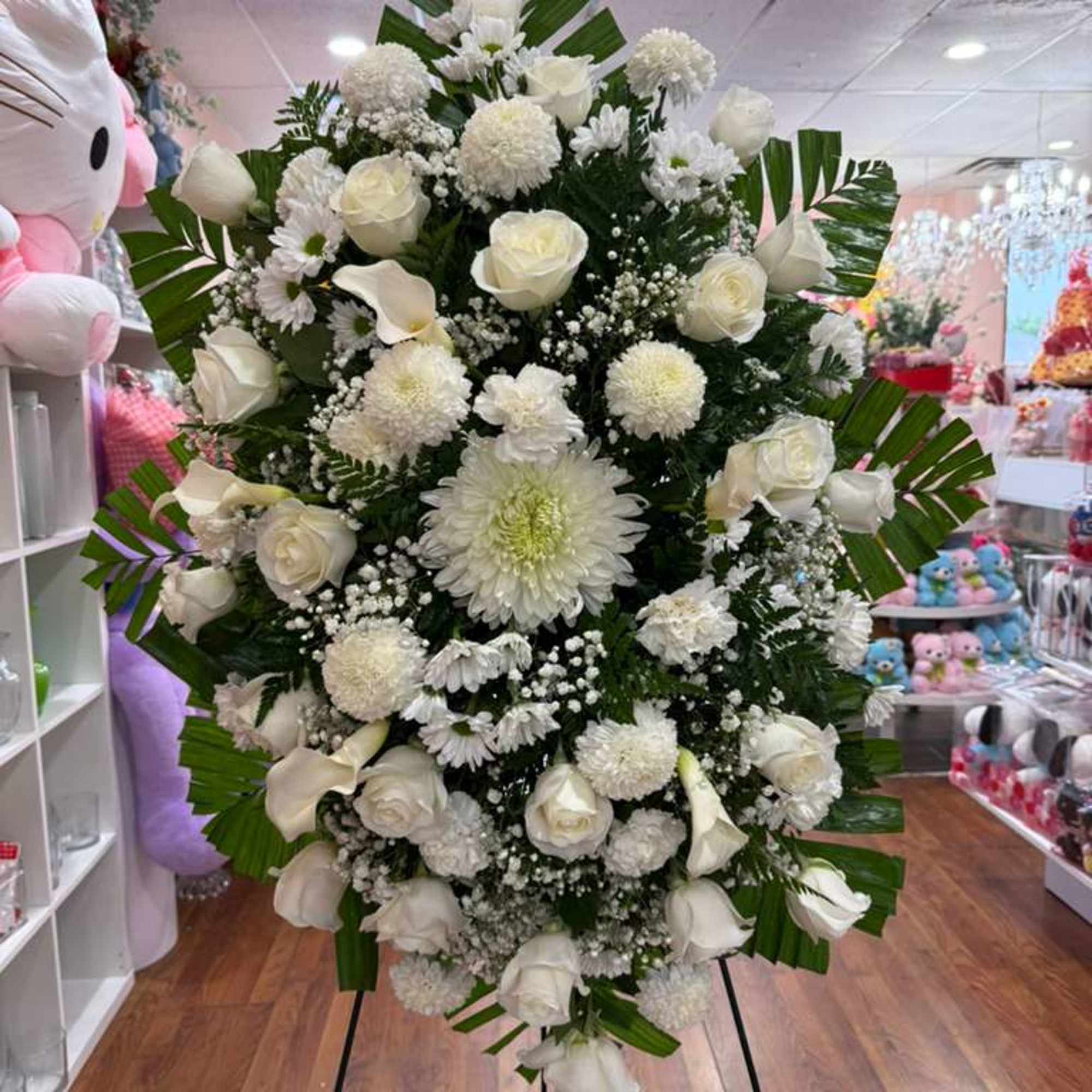 Spray of white roses, carnations, chrysanthemums, daisies, and greenery.