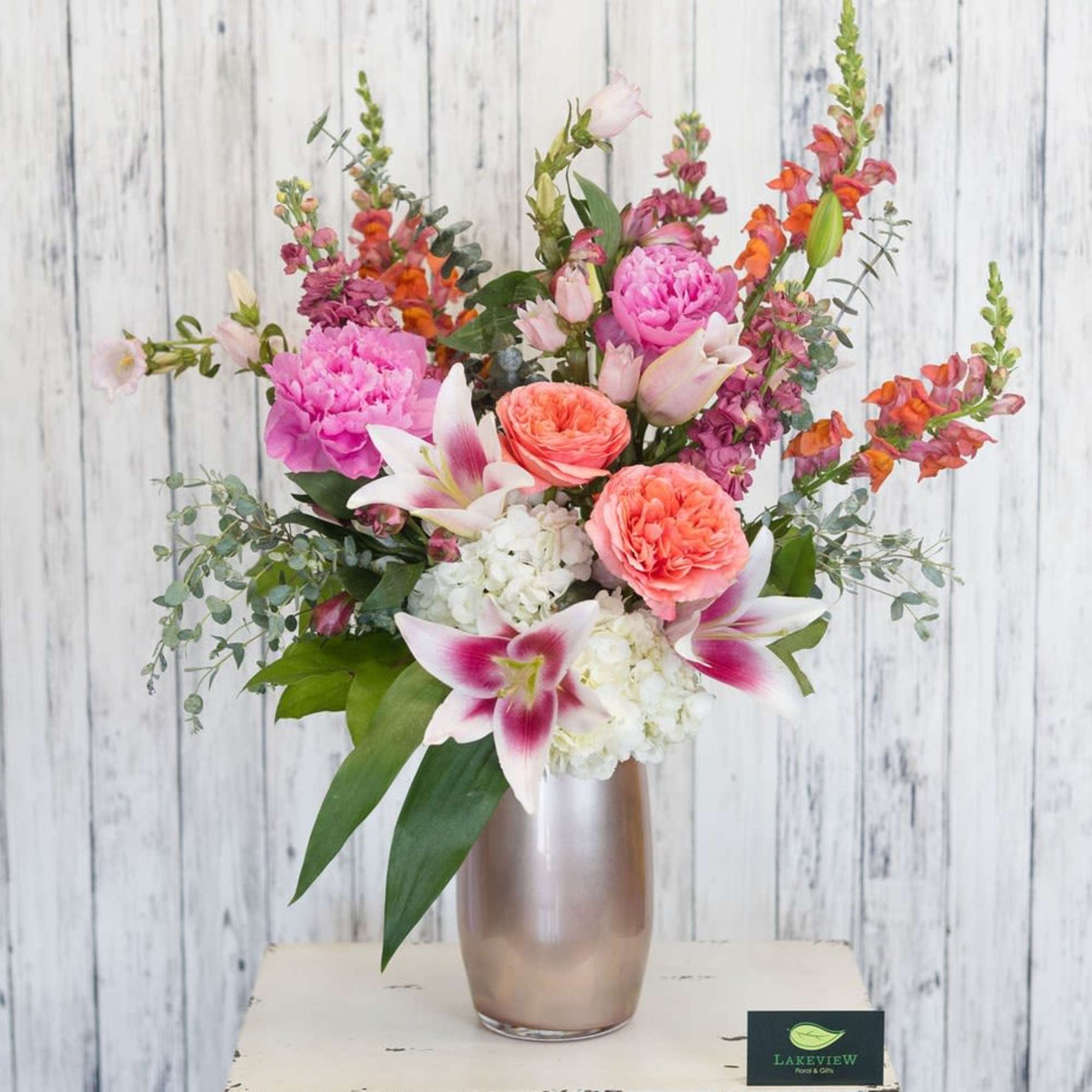 A striking, garden-style arrangement bursting with peach, orange, pink, white and touches