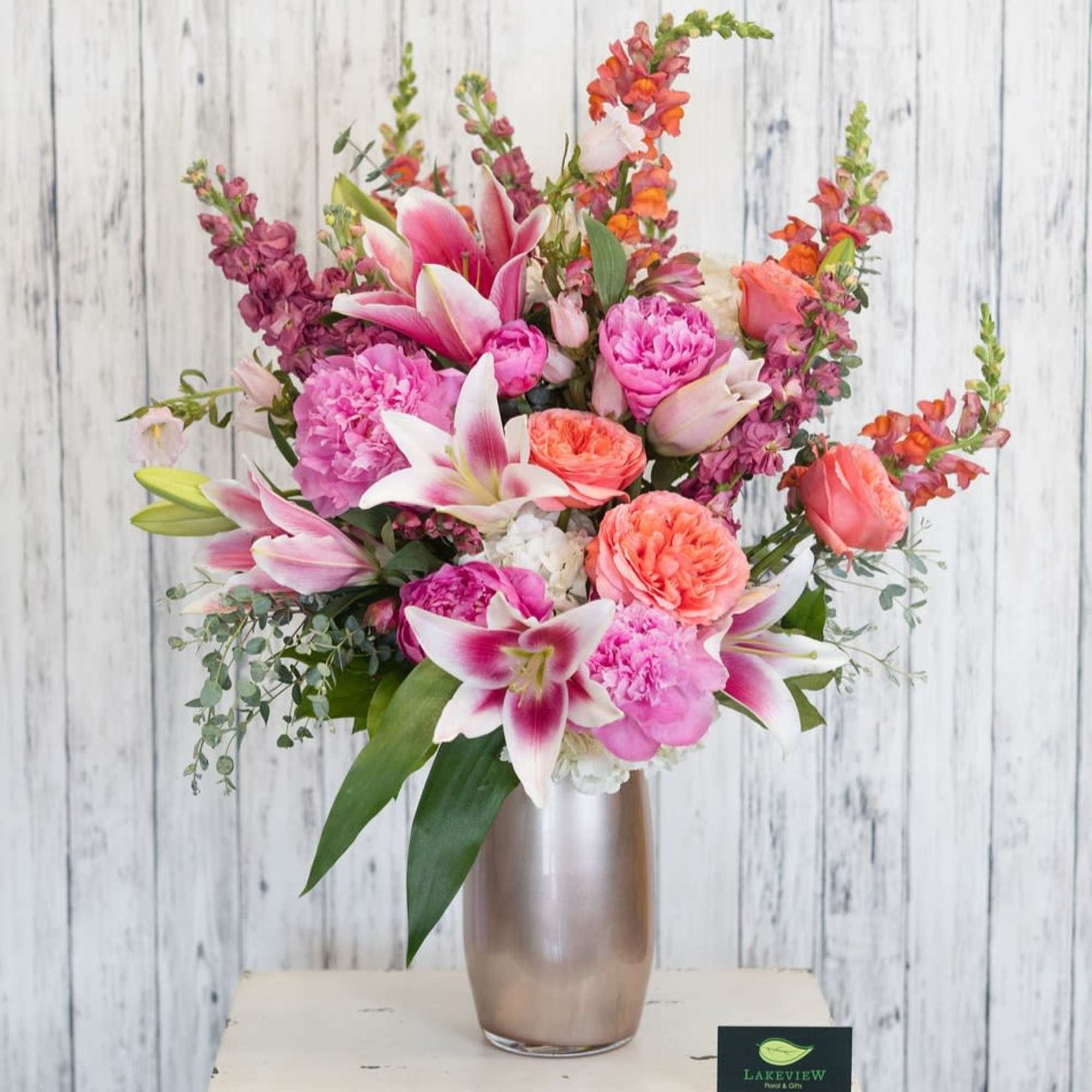 A striking, garden-style arrangement bursting with peach, orange, pink, white and touches