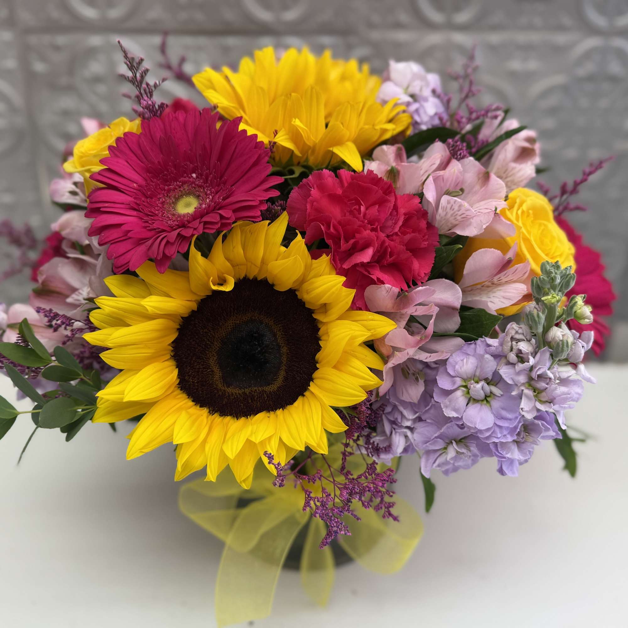 Bright mixed bouquet with sunflowers, gerbera daisies, and pink carnations in a vase