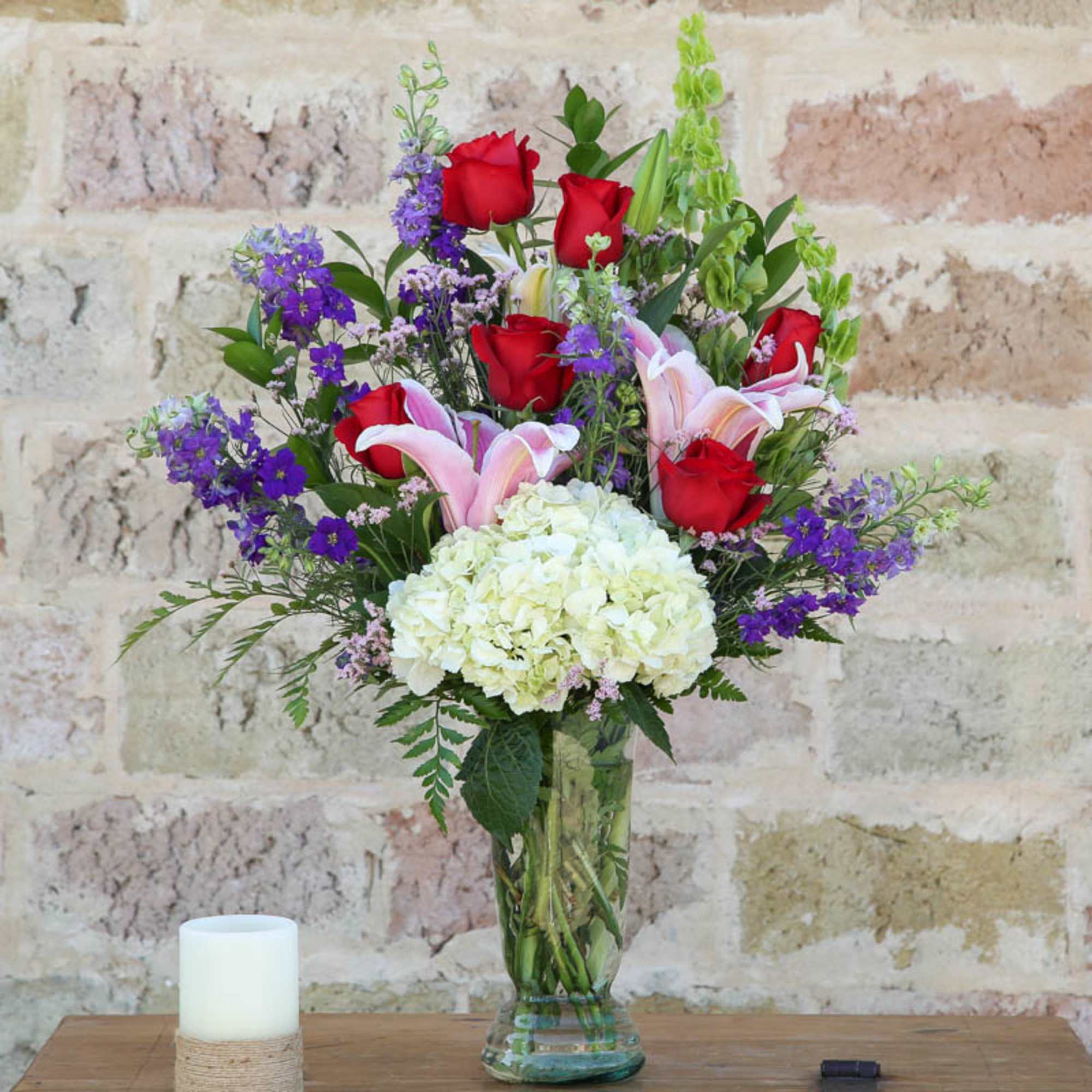 Bouquet of red roses, pink lilies, and white hydrangea in a glass vase
