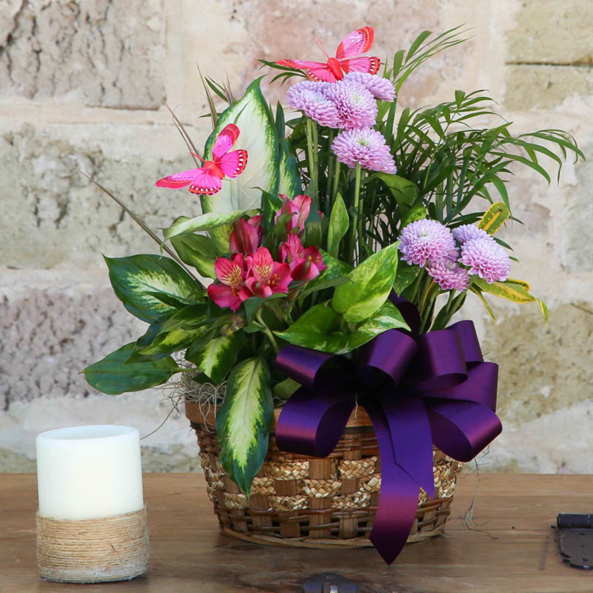 Basket arrangement with pink flowers, purple blooms, and a large purple ribbon