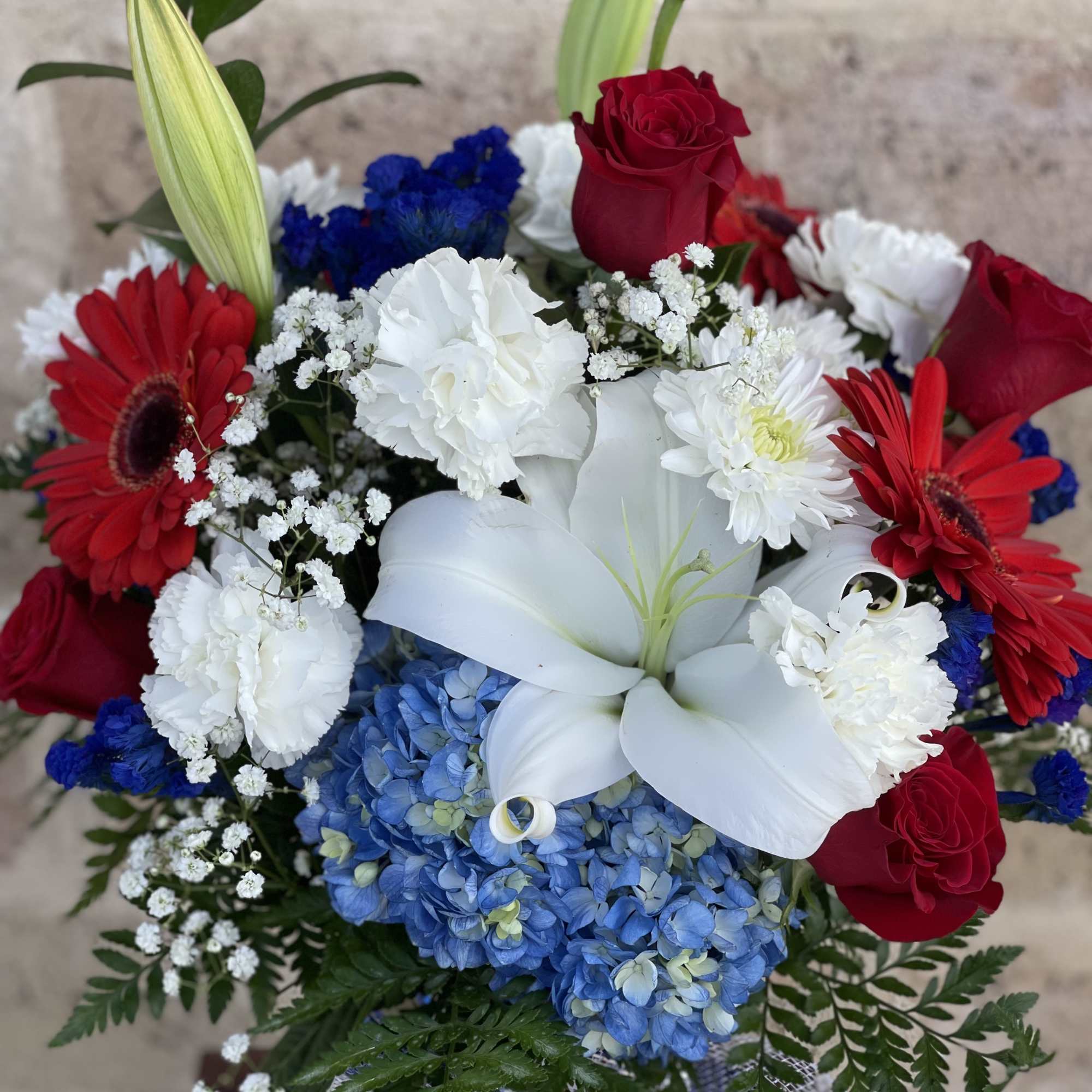 Bouquet of red roses, white lilies, blue hydrangea, and red gerbera daisies