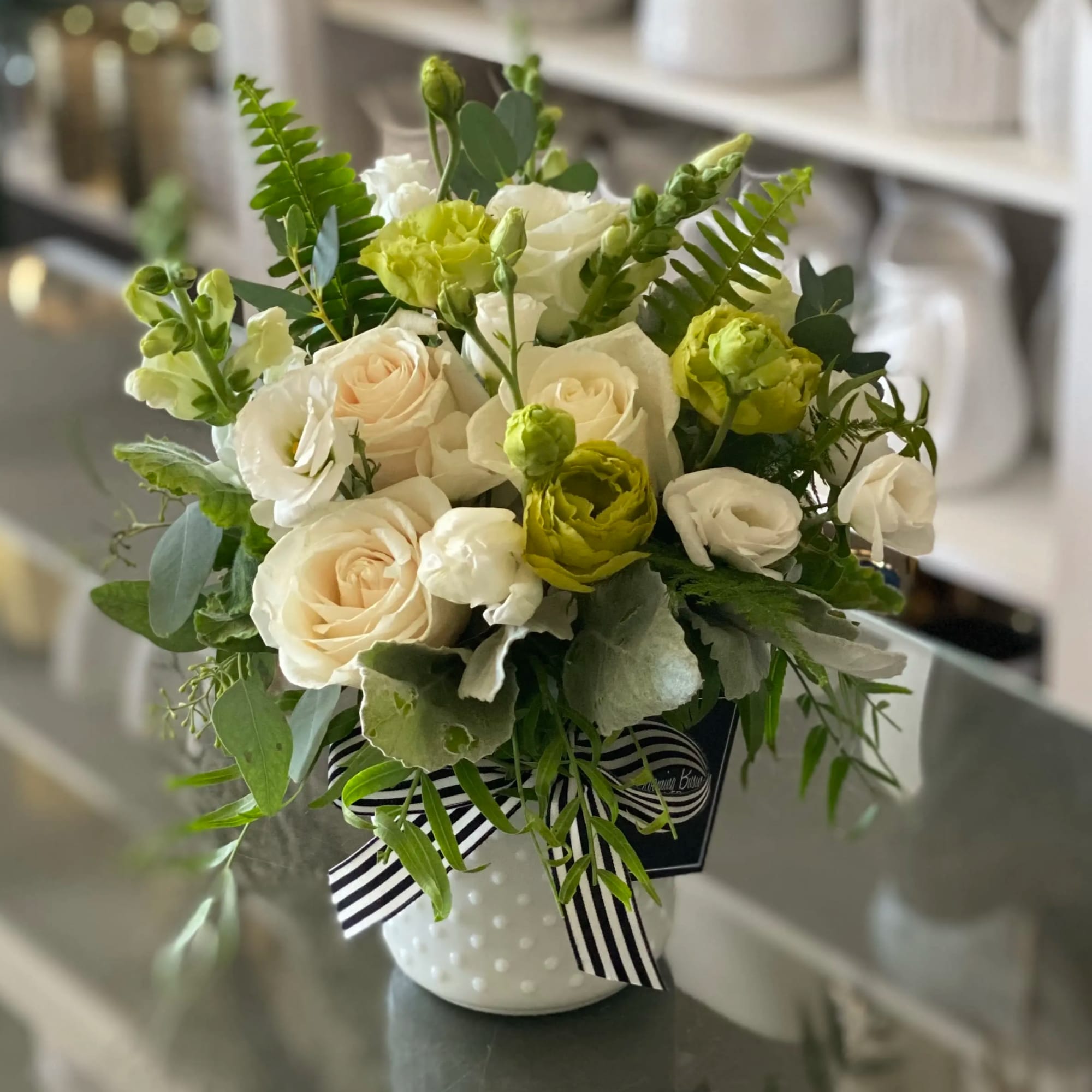 White and pale peach roses with green blooms in a white vase