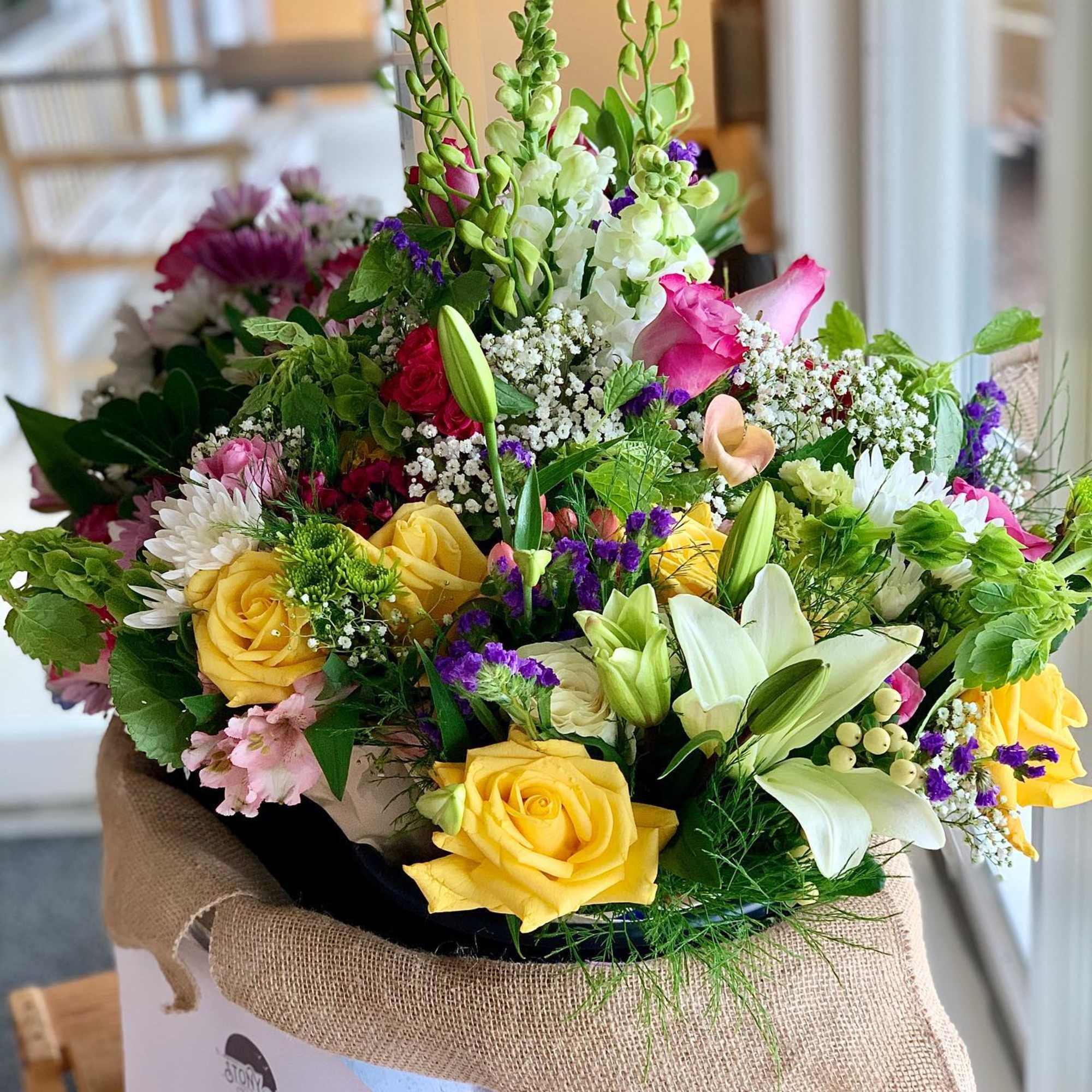 Mixed bouquet with yellow roses, white lilies, and pink blooms in a wrapped box
