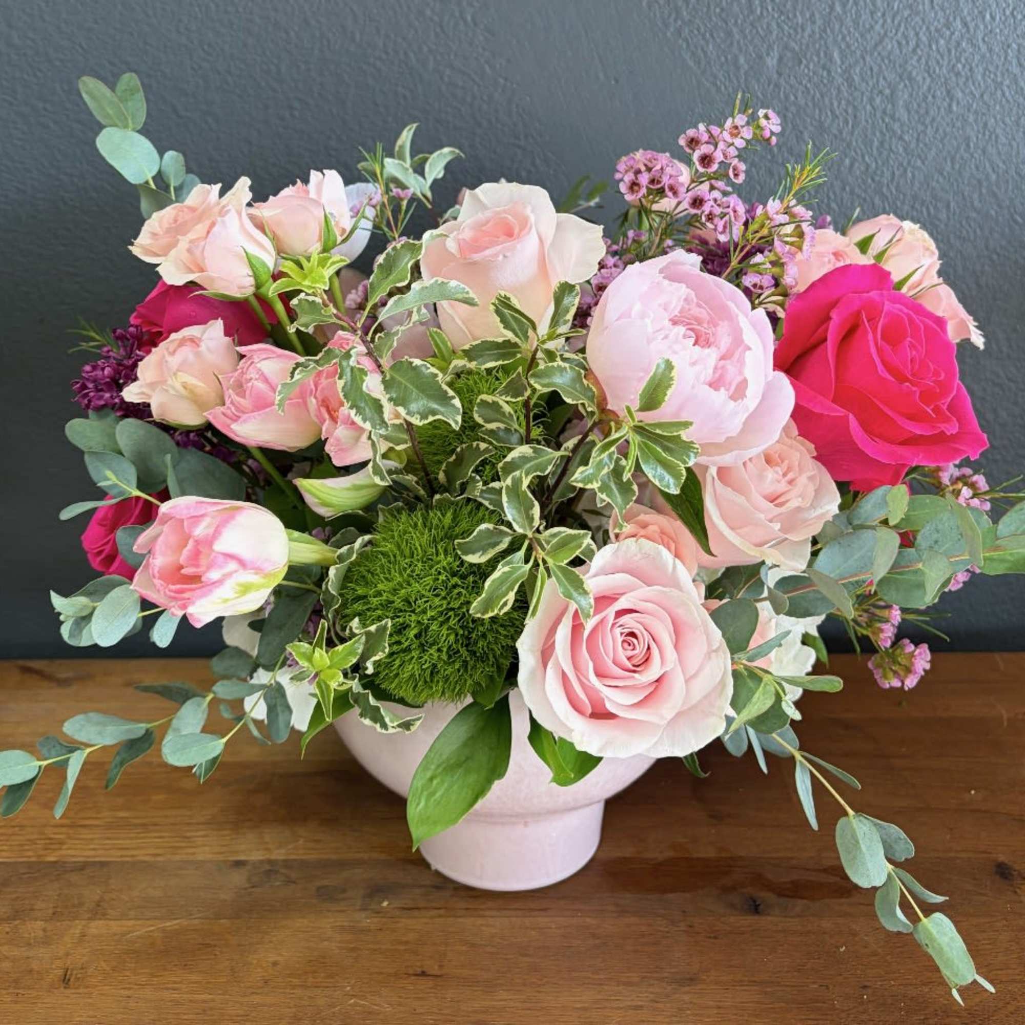 A romantic and artfully gathered arrangement in soft blush, ivory, and vibrant