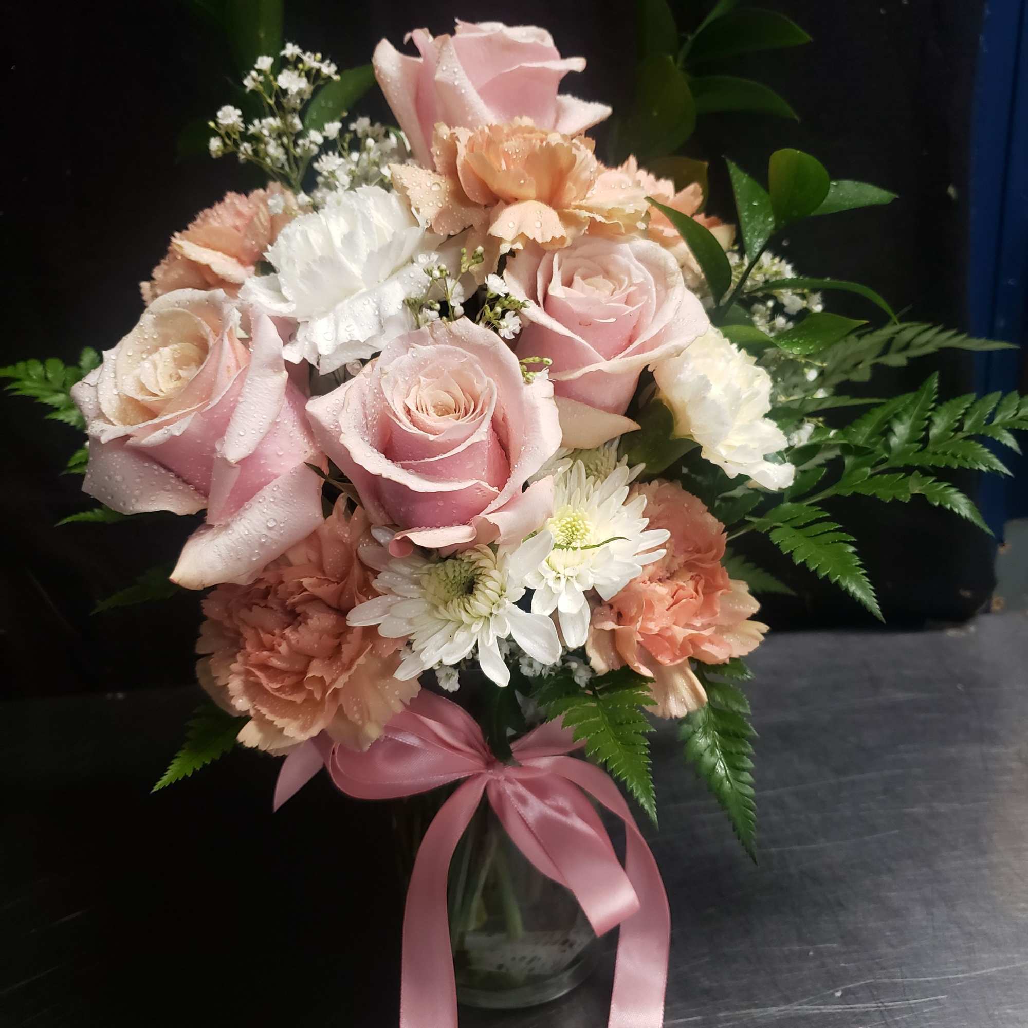Soft pink roses and peach-and-white carnations mingle with tiny white daisy-like blooms
