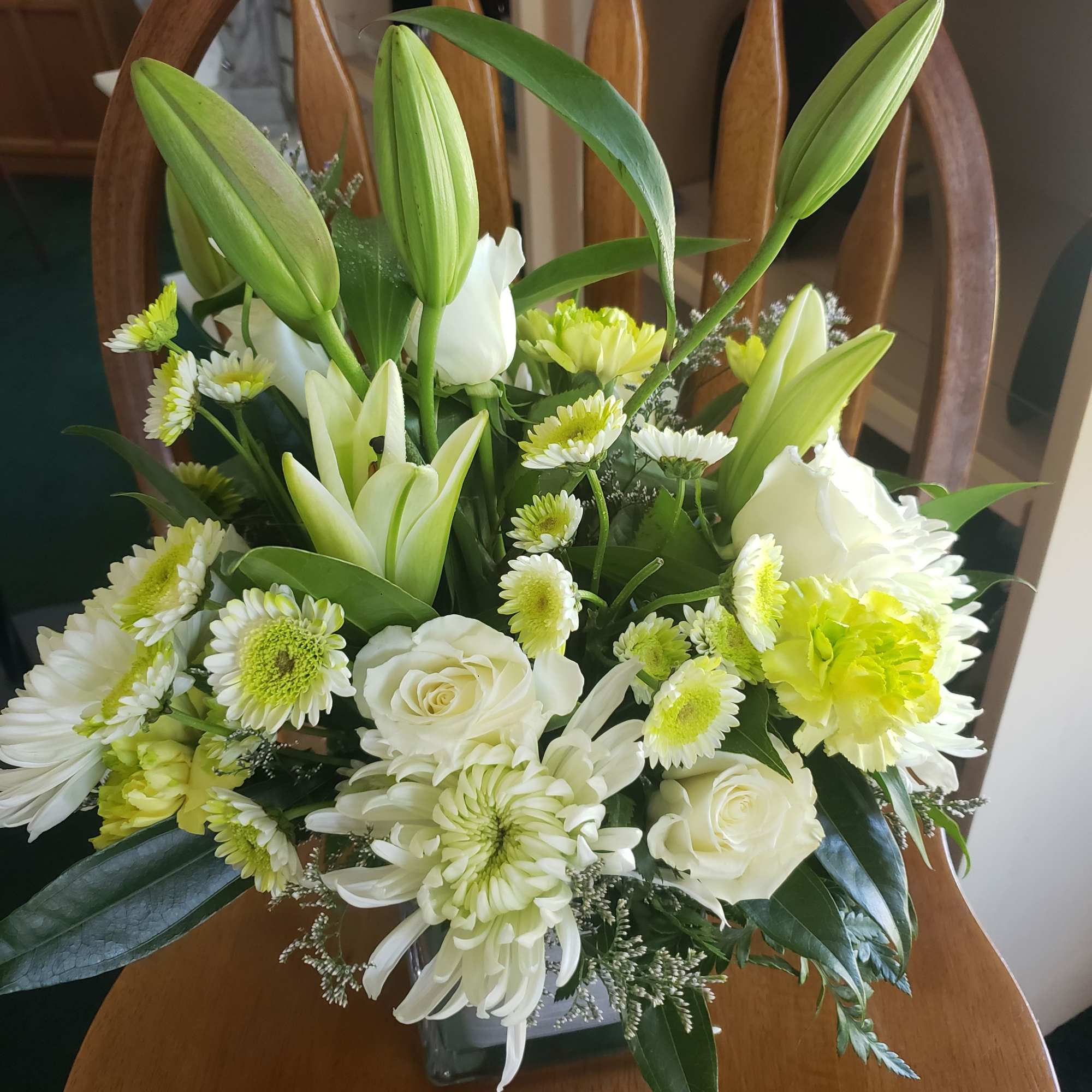 A tall, graceful standing spray of soft pink roses, white lilies, and