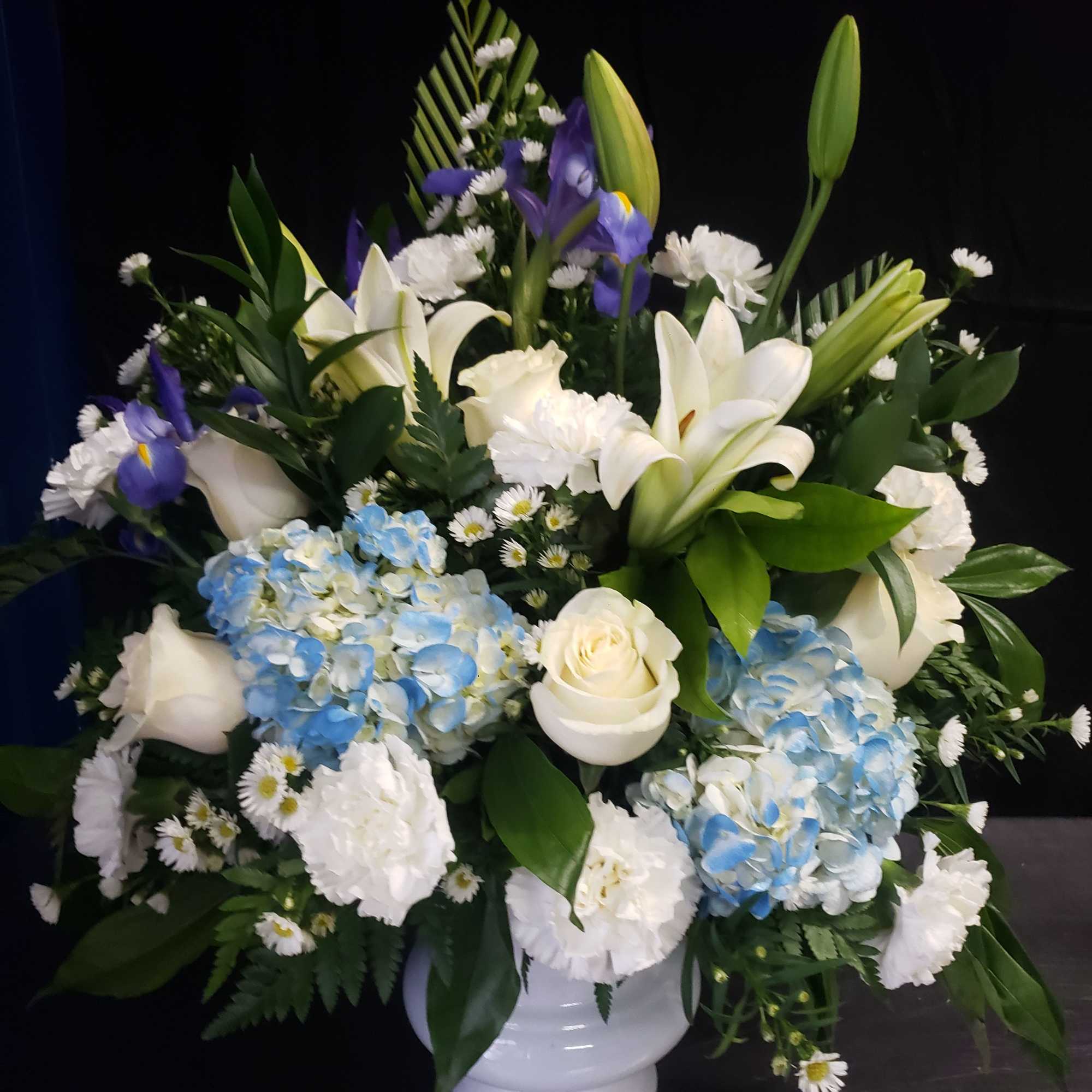 A tall, graceful standing spray of soft pink roses, white lilies, and