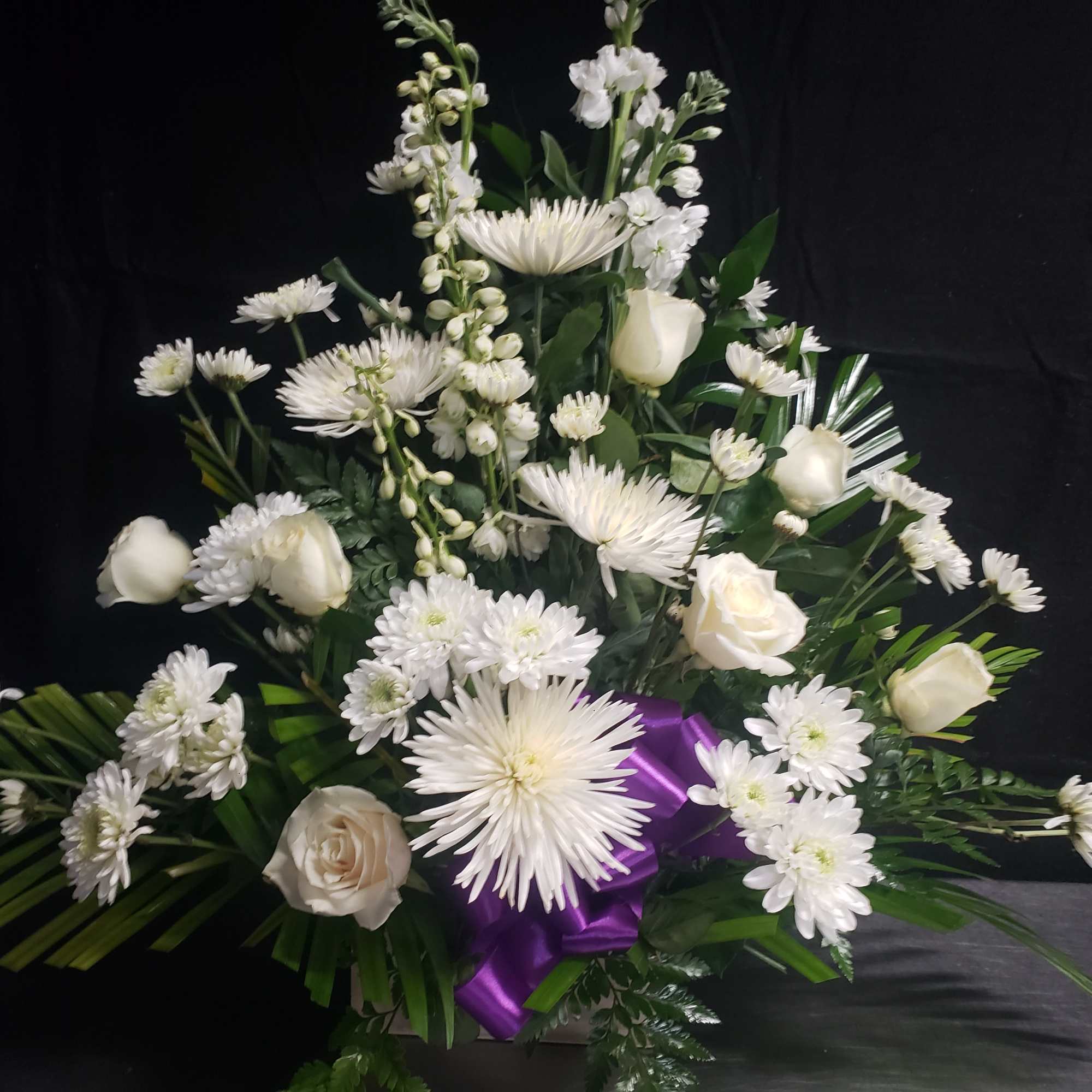 A tall, graceful standing spray of soft pink roses, white lilies, and