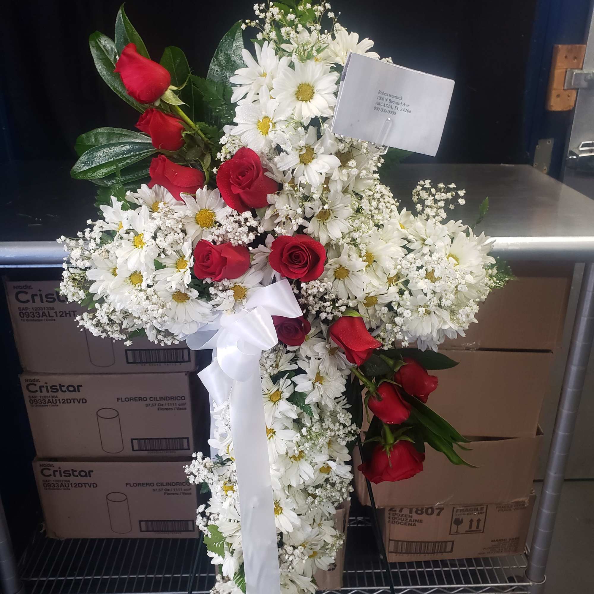 A tall, graceful standing spray of soft pink roses, white lilies, and