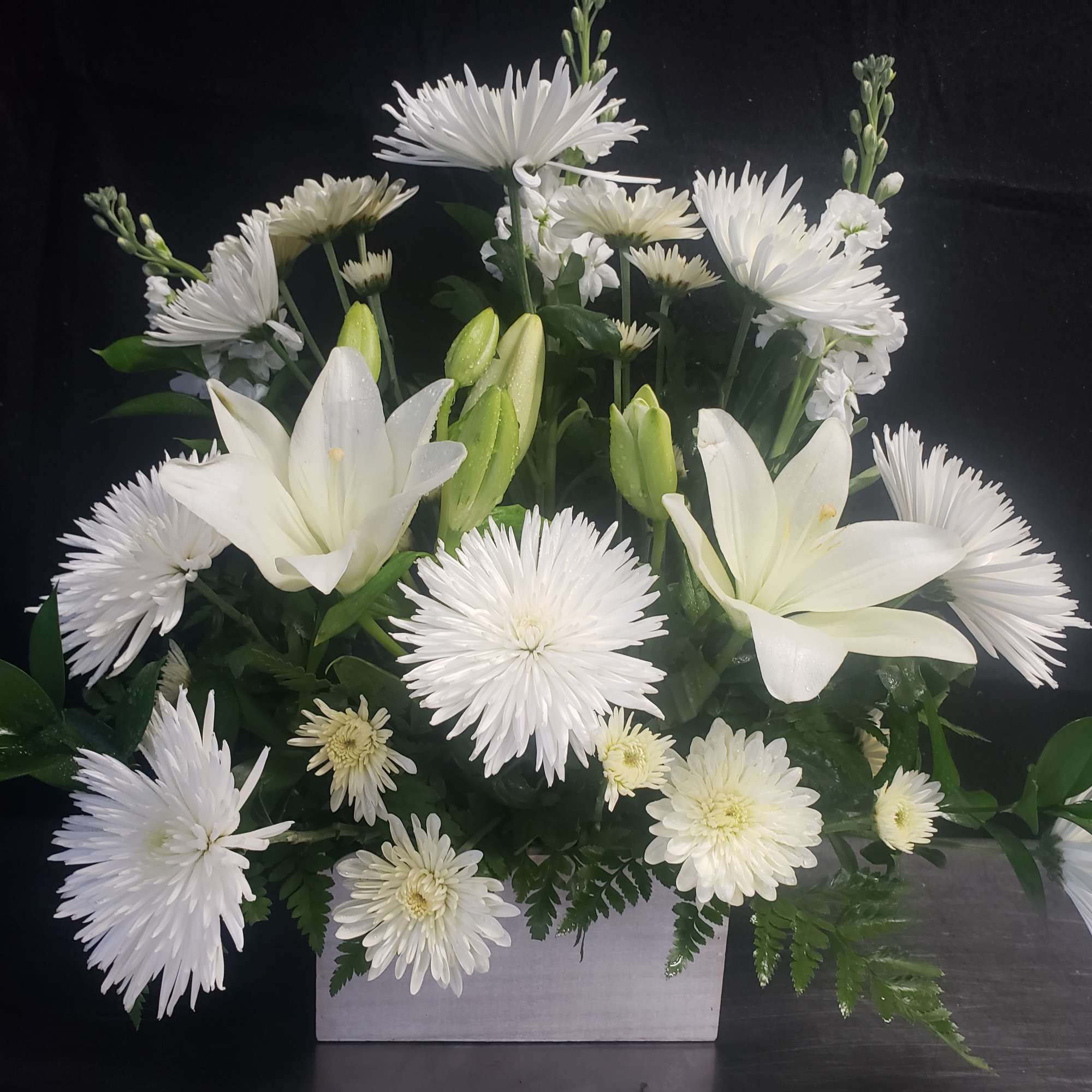A tall, graceful standing spray of soft pink roses, white lilies, and