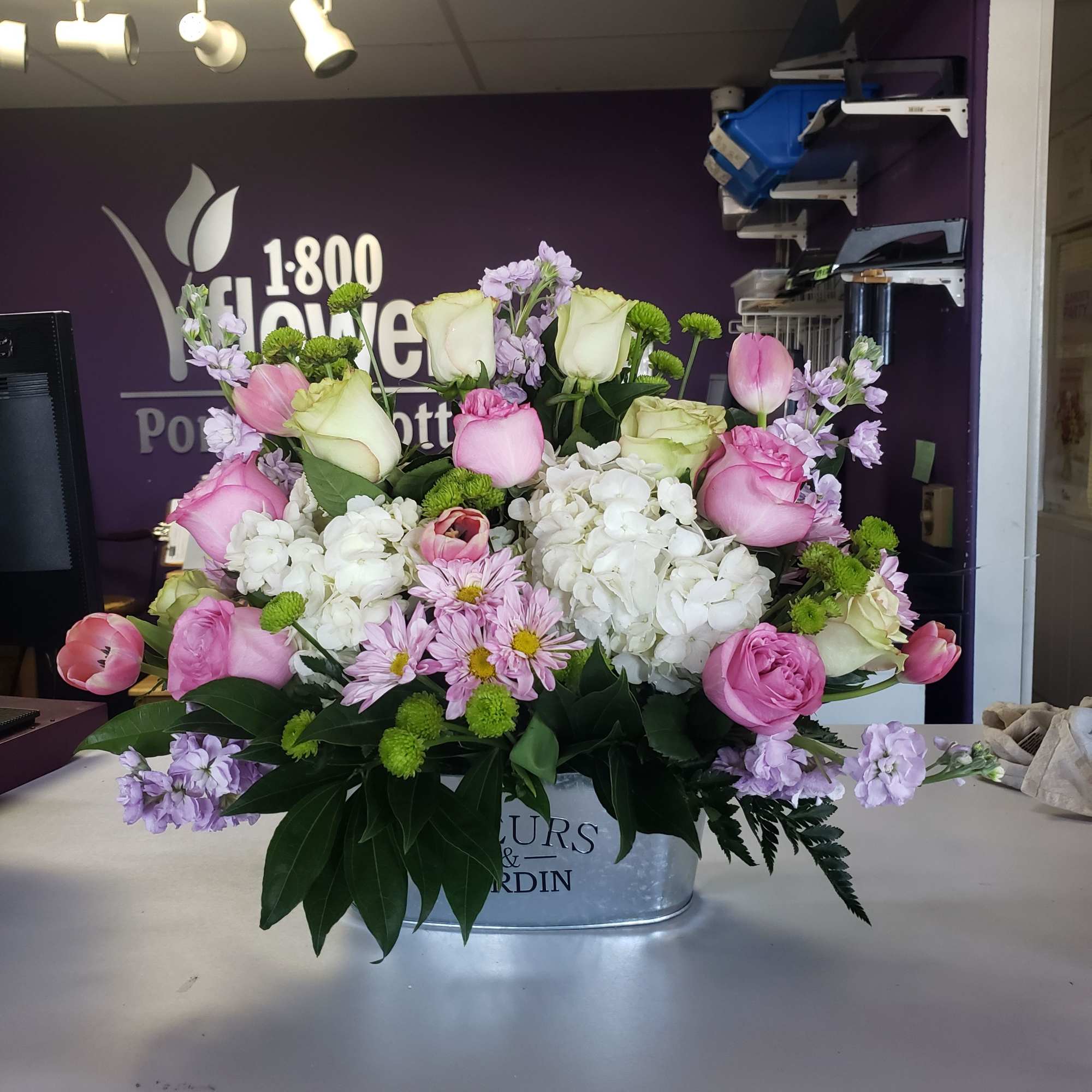 A tall, graceful standing spray of soft pink roses, white lilies, and