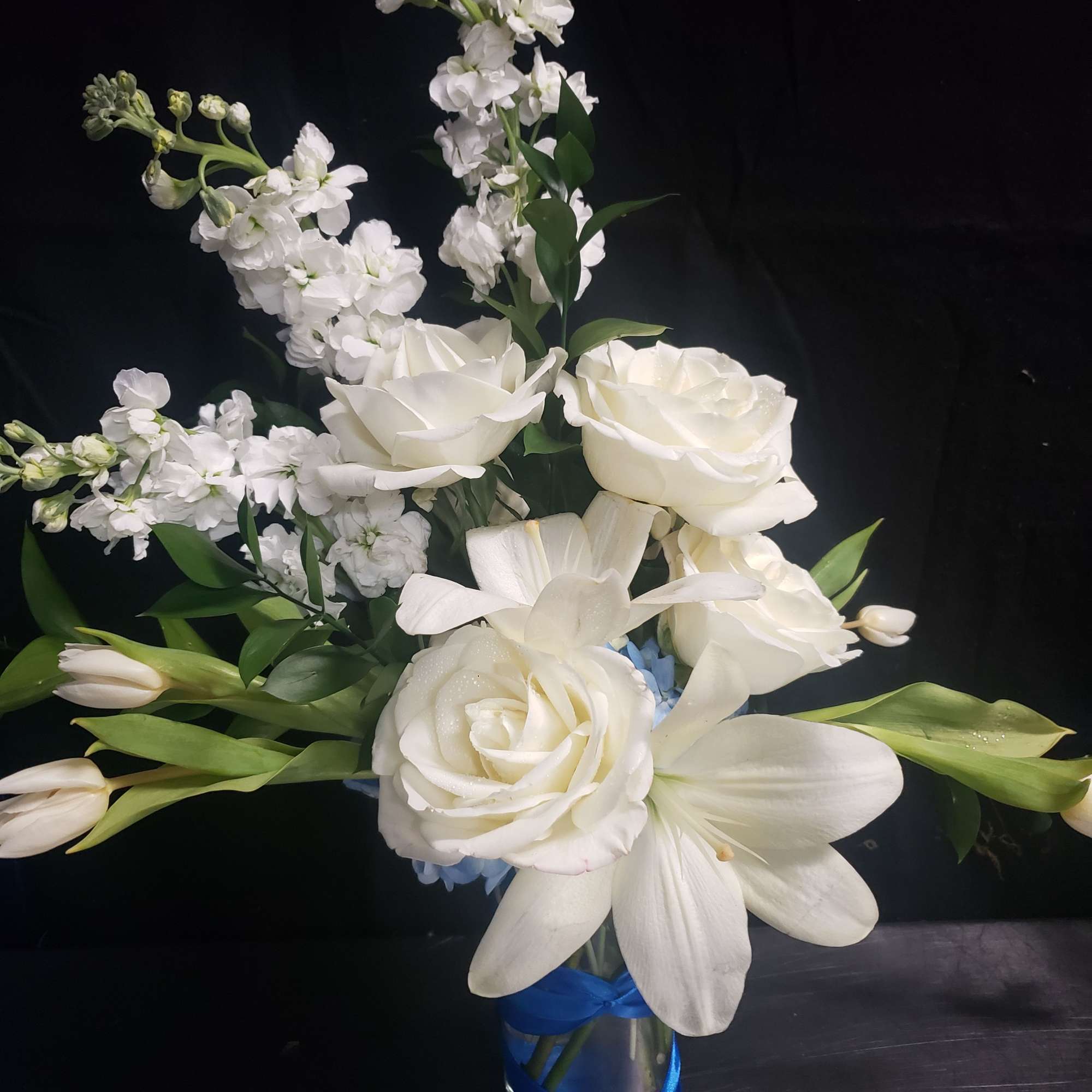 A tall, graceful standing spray of soft pink roses, white lilies, and