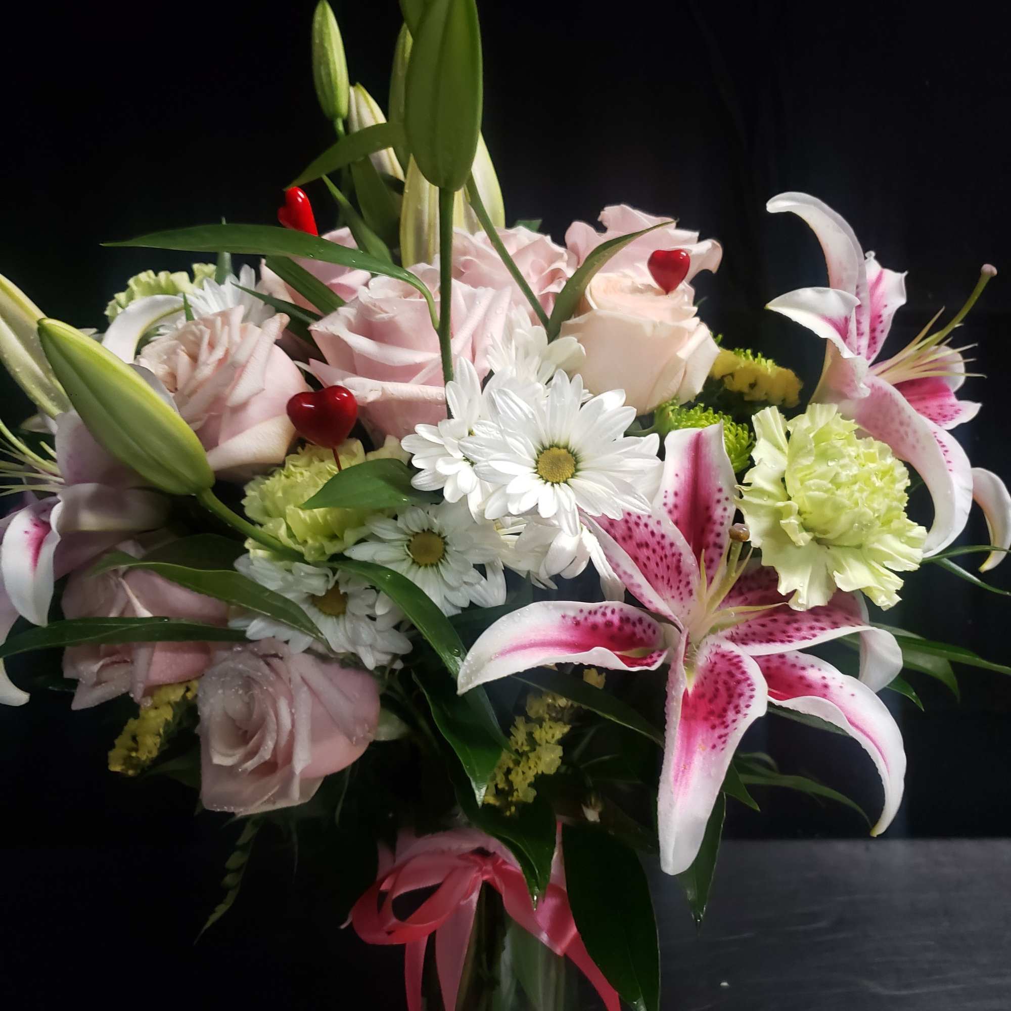 A tall, graceful standing spray of soft pink roses, white lilies, and