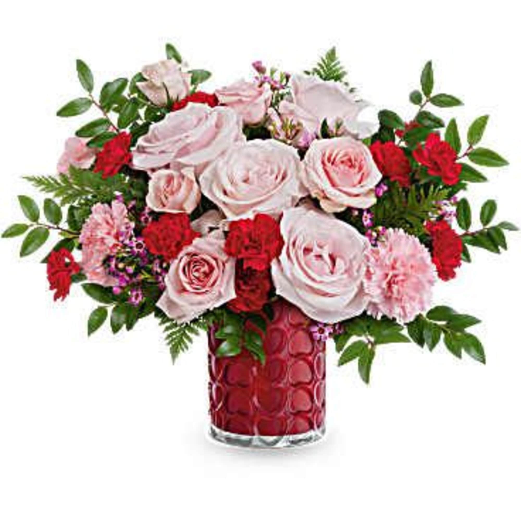 Pink and red rose arrangement in a red glass vase