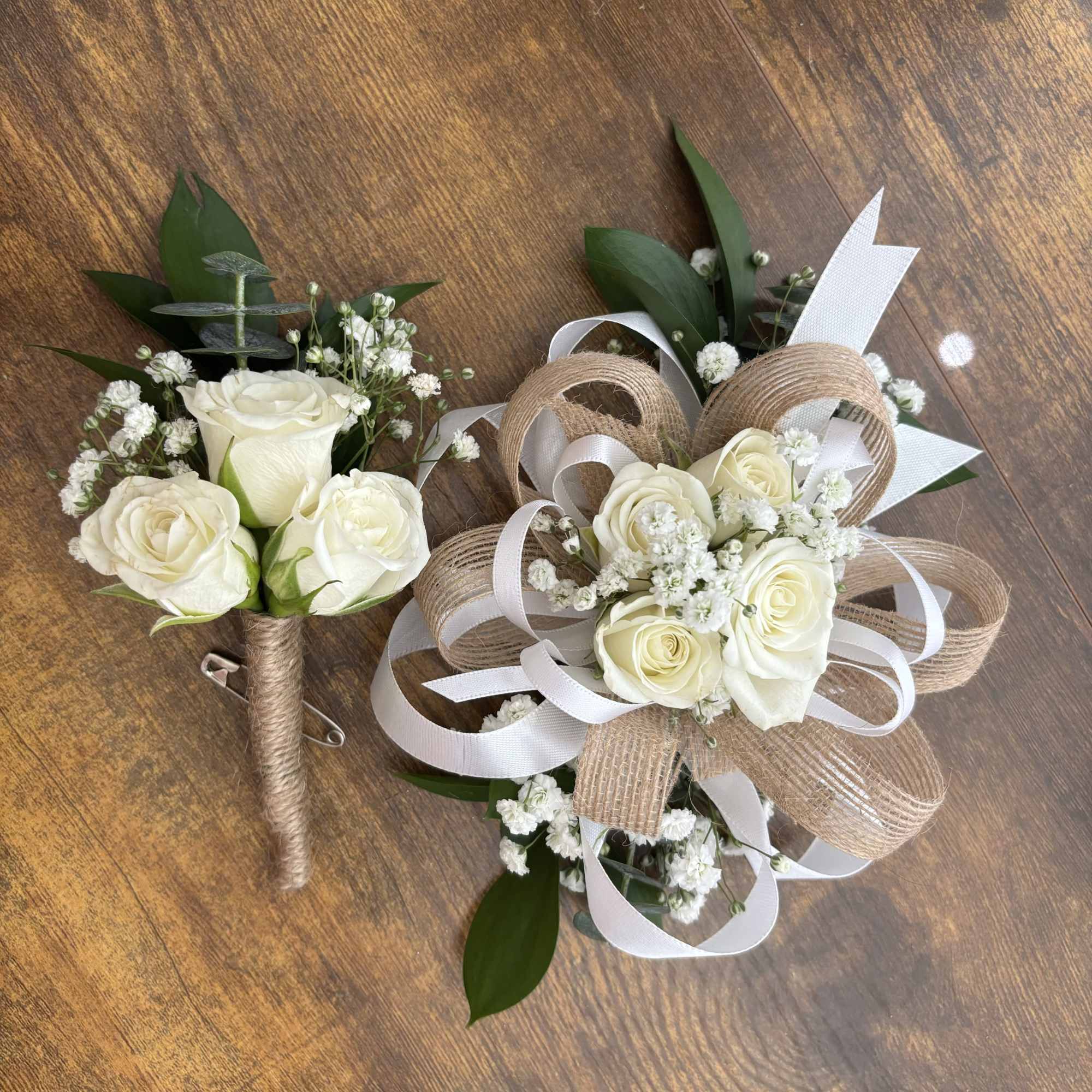 Two white rose boutonnieres with ribbon and baby's breath