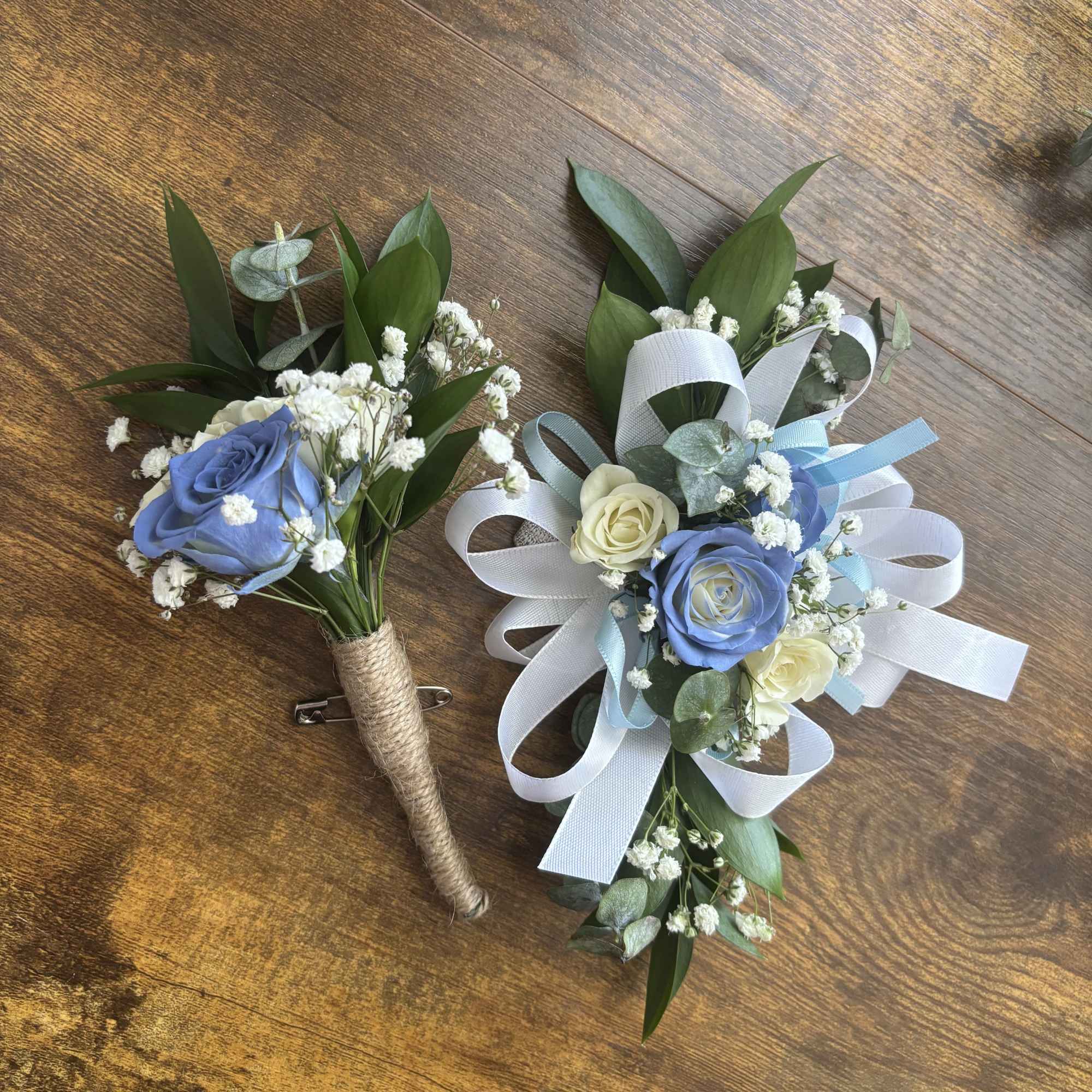Two small blue and white rose boutonnieres with ribbon loops