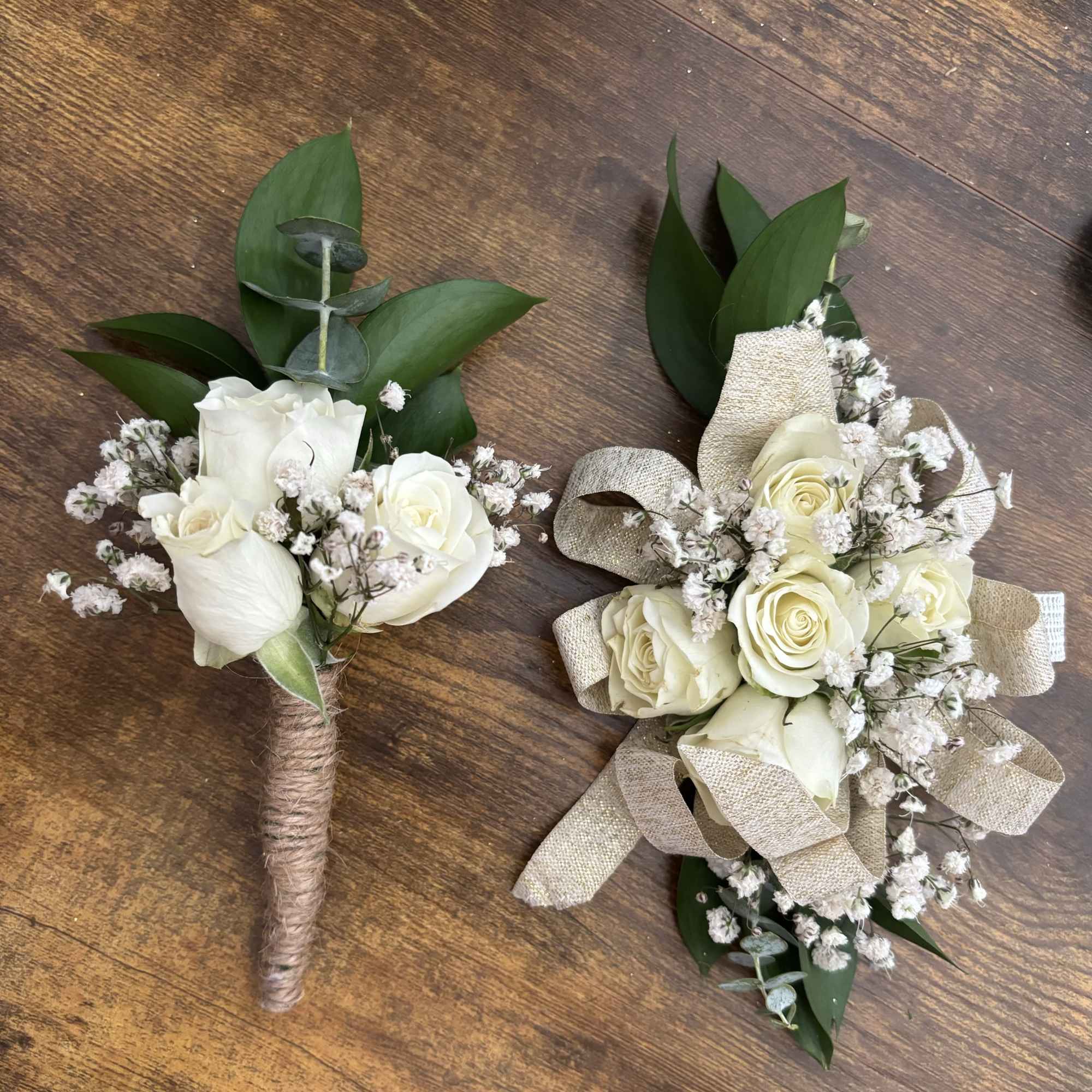 Two white rose boutonnieres with baby's breath and ribbon wrap