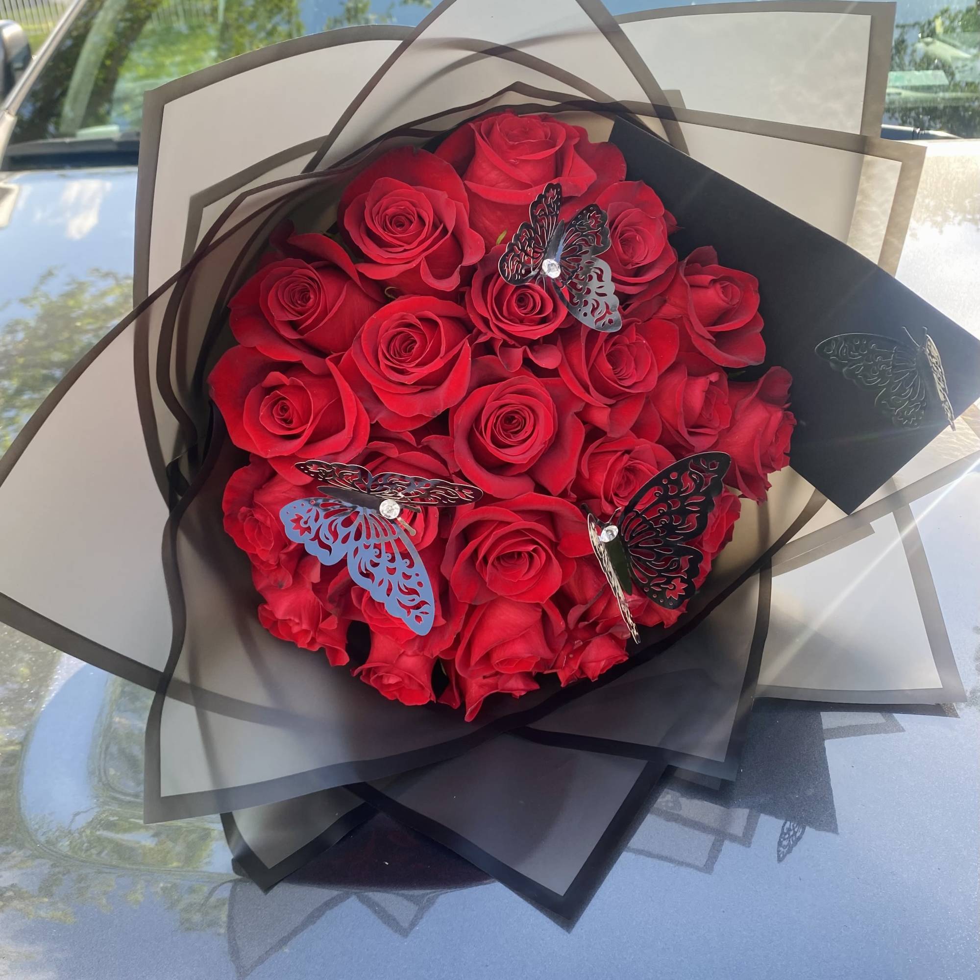 Bouquet of red roses wrapped in black and white paper with butterfly accents