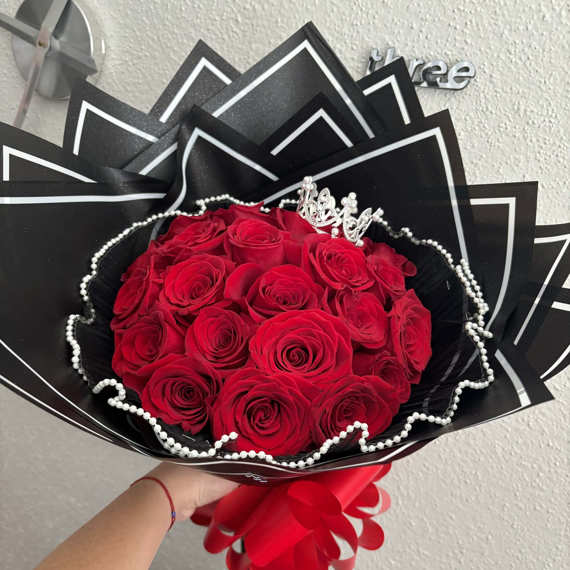 Bouquet of red roses wrapped in black paper with white trim and pearl accents
