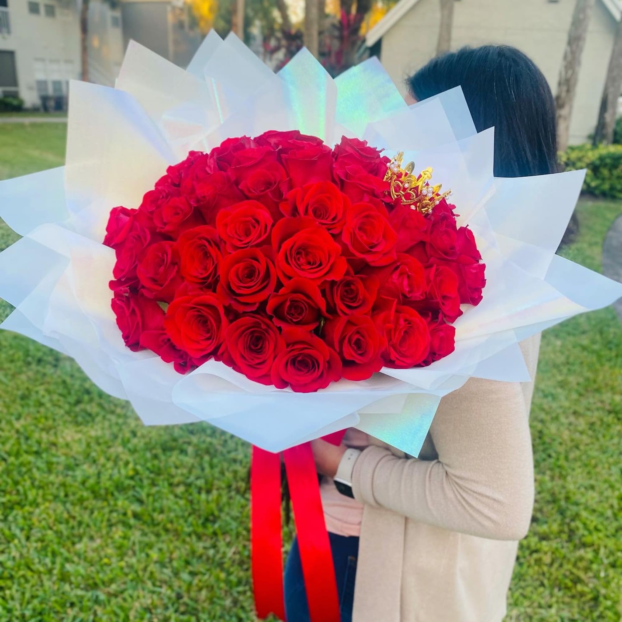 Large bouquet of red roses wrapped in white paper with a red ribbon