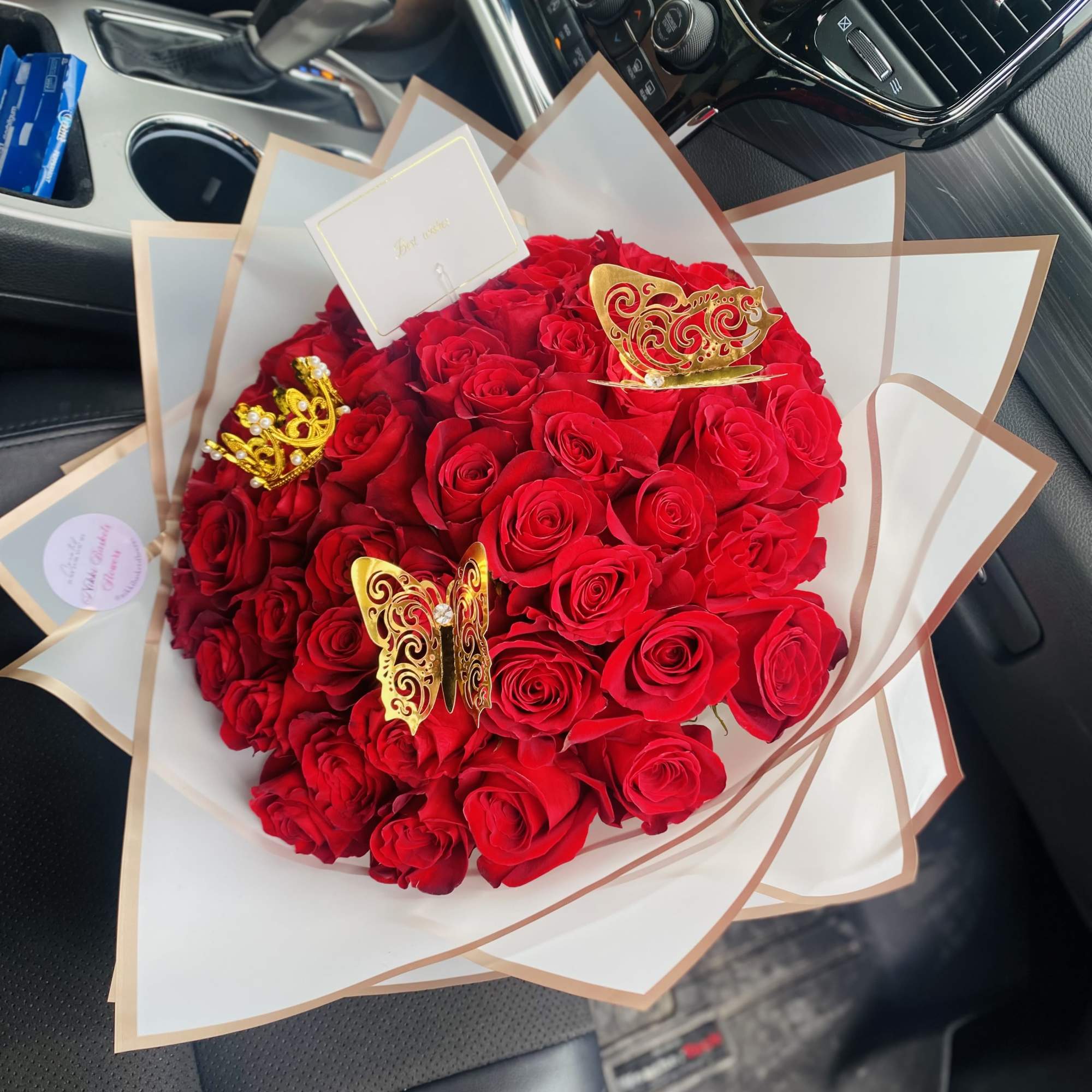 Bouquet of red roses wrapped in white paper with gold butterfly accents