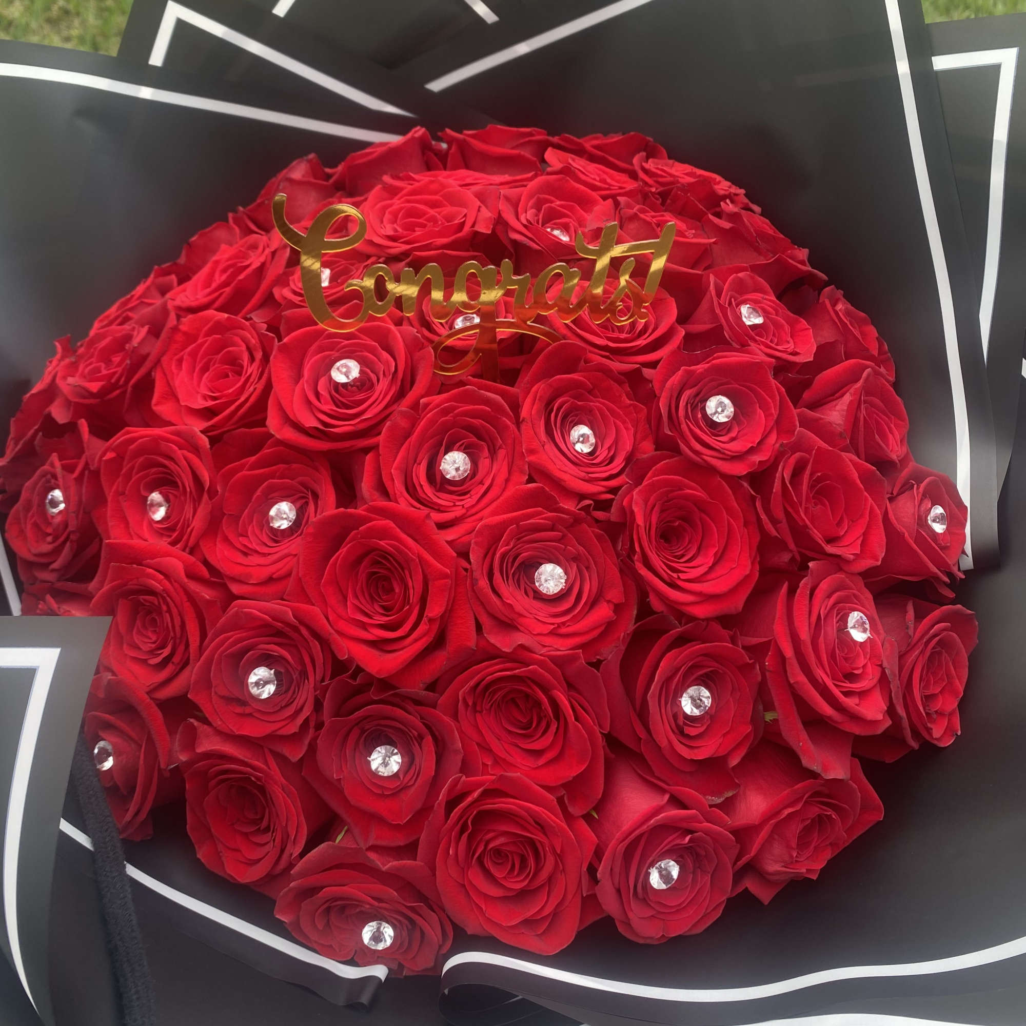 Bouquet of red roses with a gold "Congrats" topper