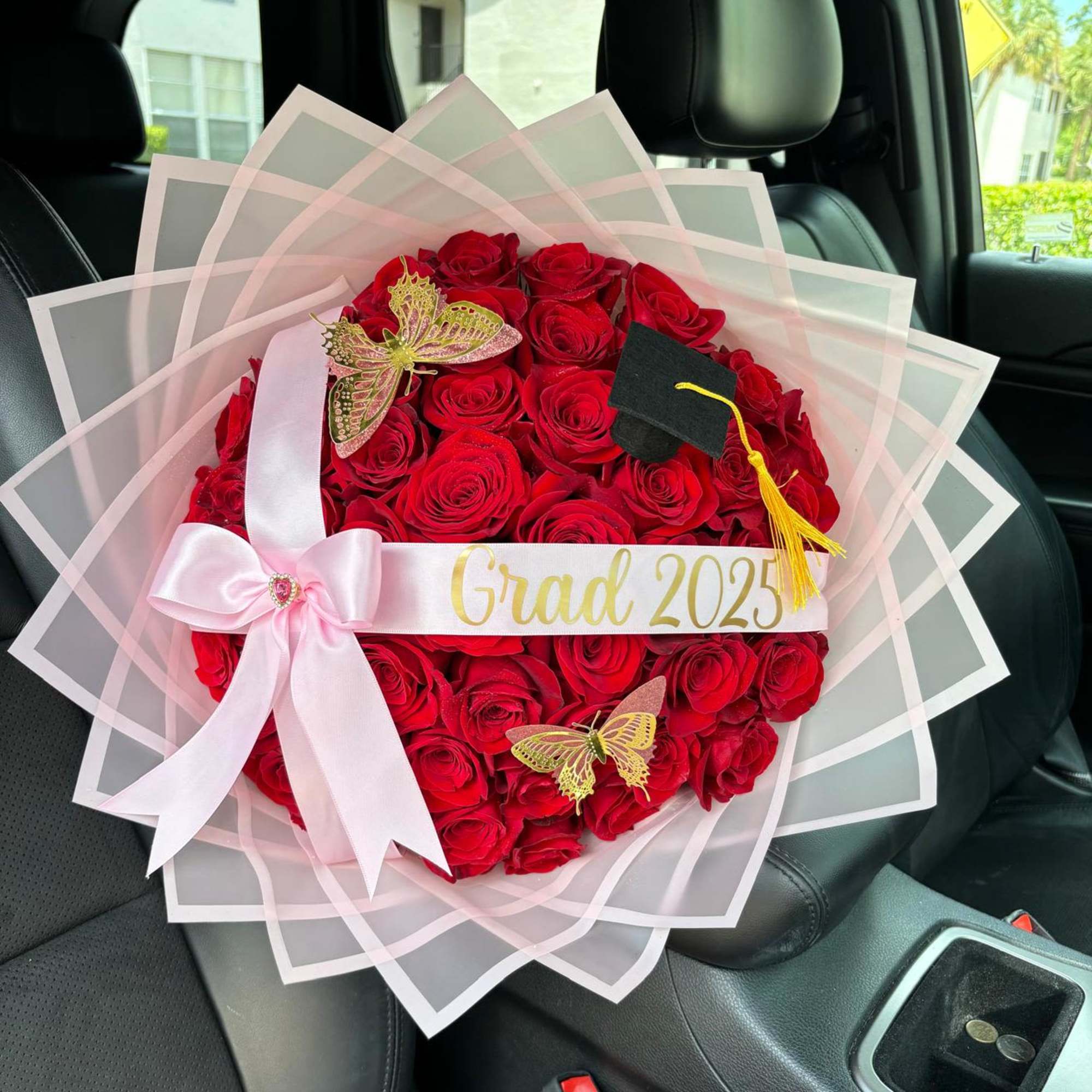 Heart-shaped bouquet of red roses with a pink ribbon and graduation sash