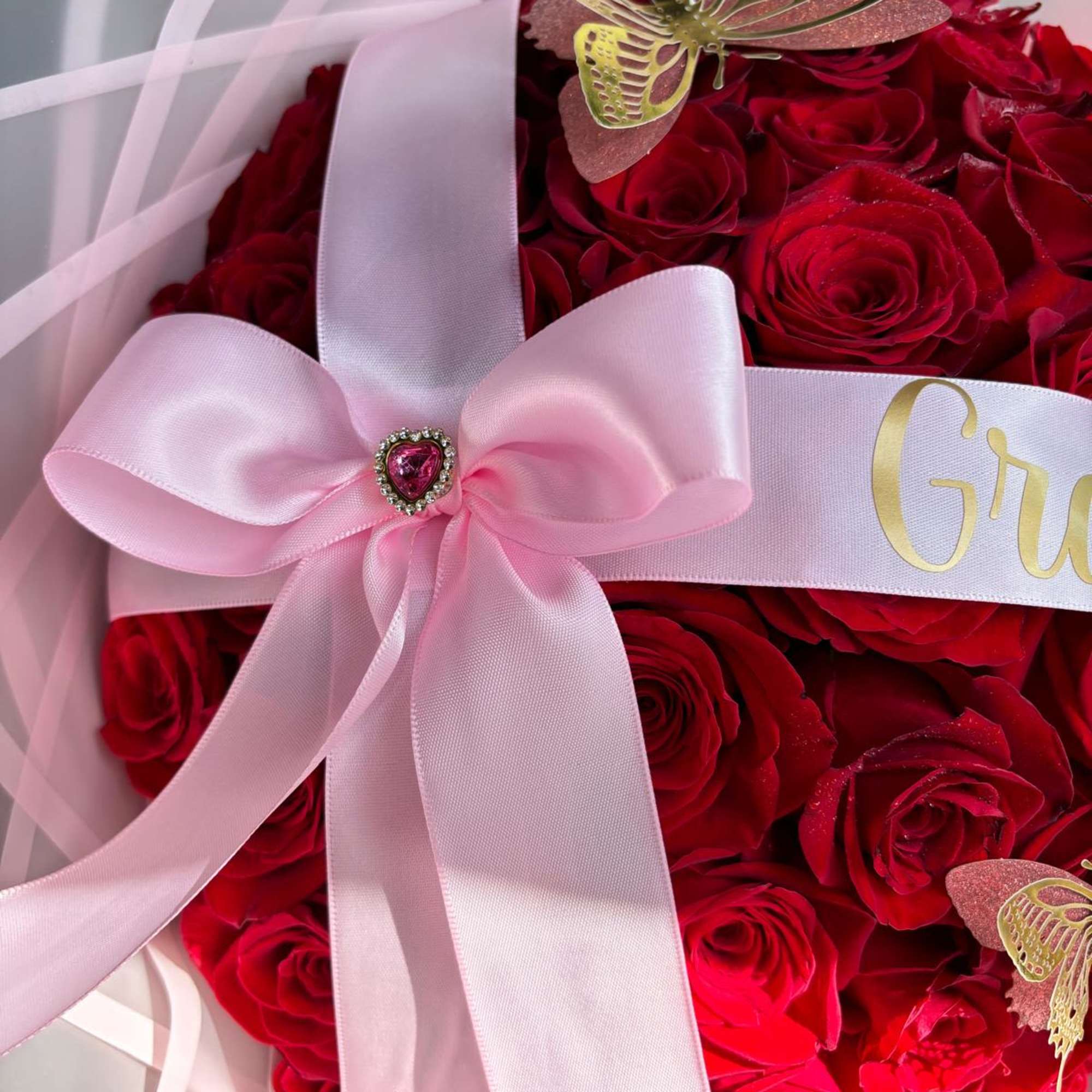 Red rose bouquet with a pink ribbon bow and butterfly accents