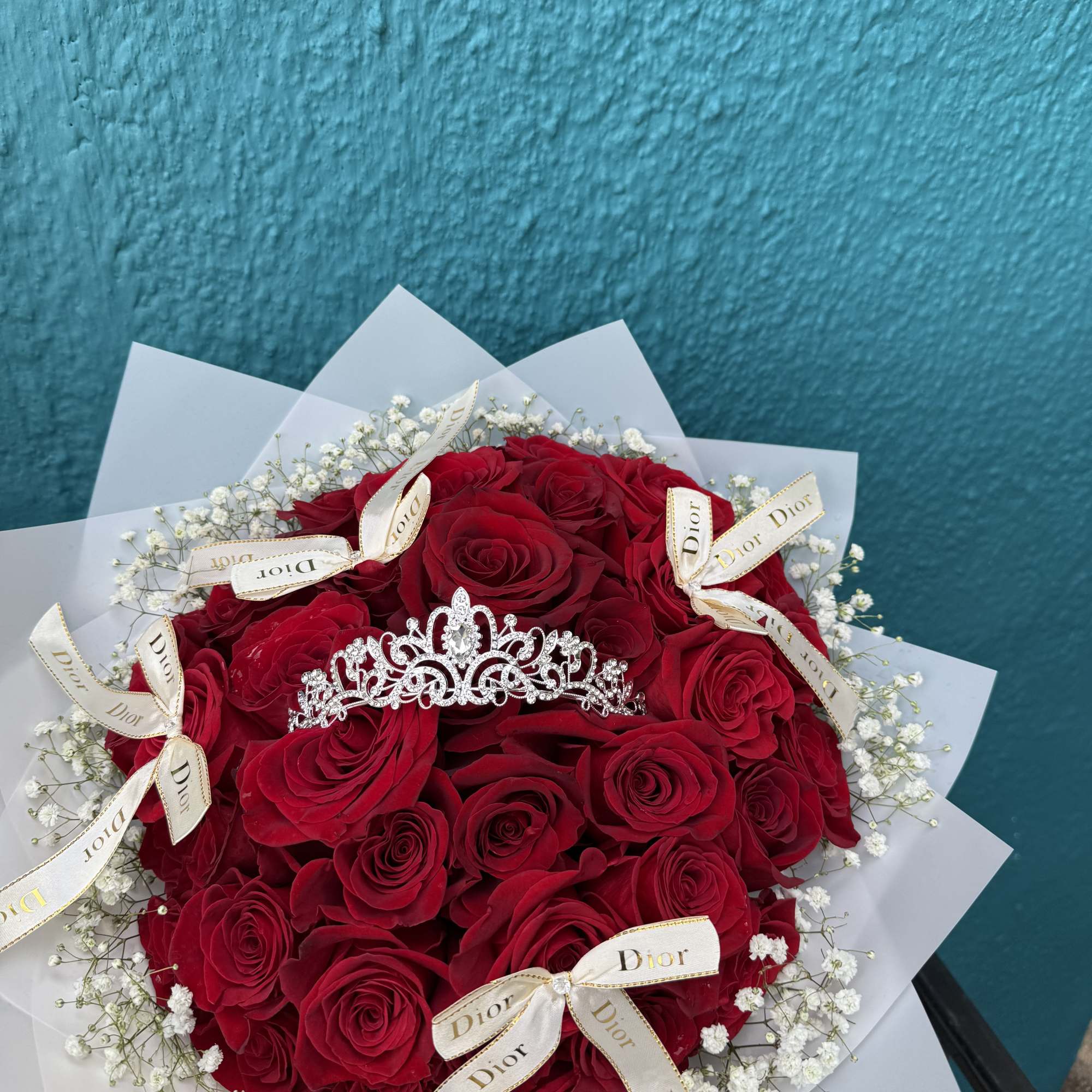 Bouquet of red roses with white baby's breath, tiara centerpiece, and Dior ribbons